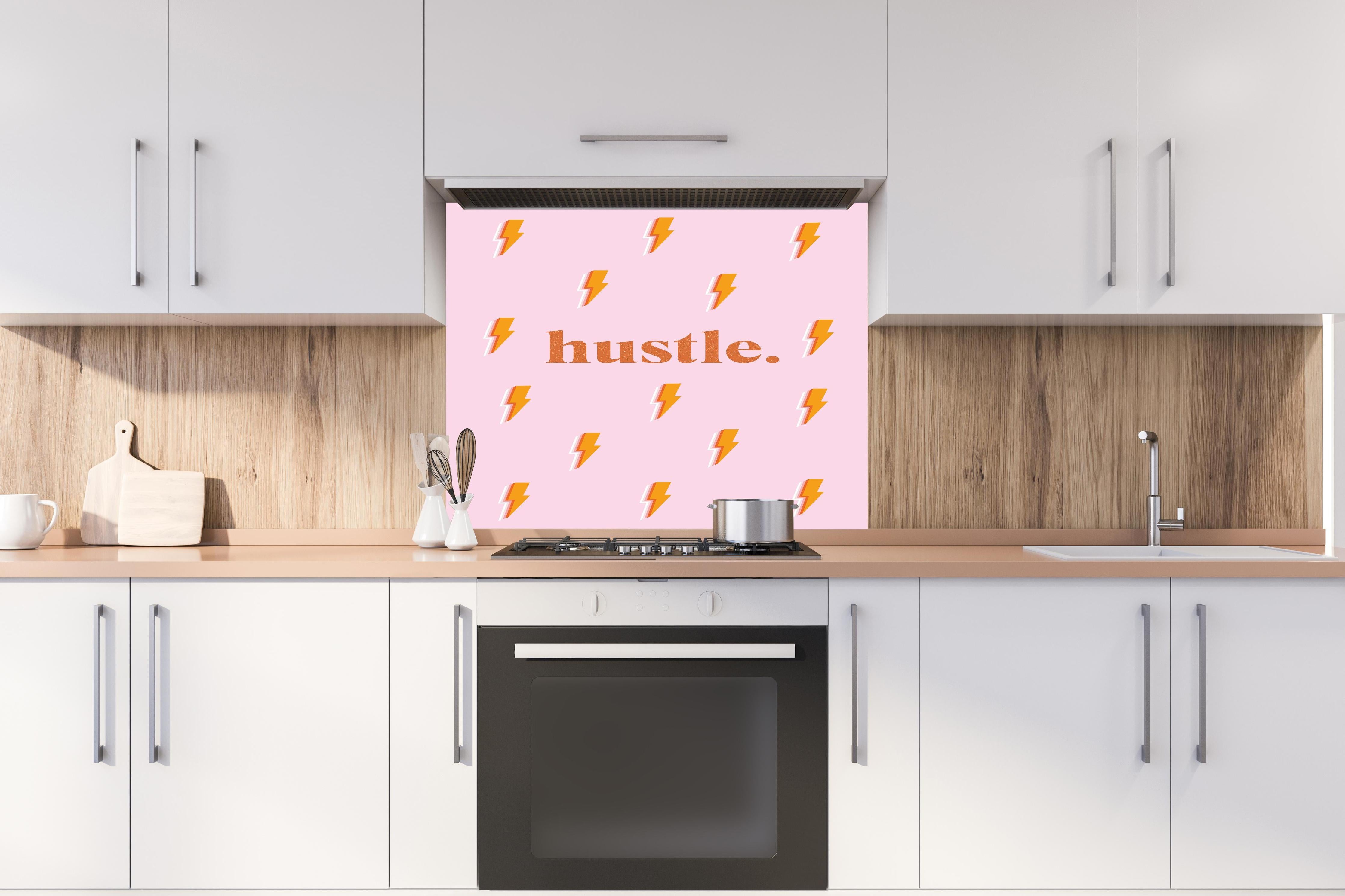 Spritzschutz - Inspirierendes Blitz-Motiv in Pink und Orange hinter einem Cerankochfeld zwischen Holz-Kochutensilien
