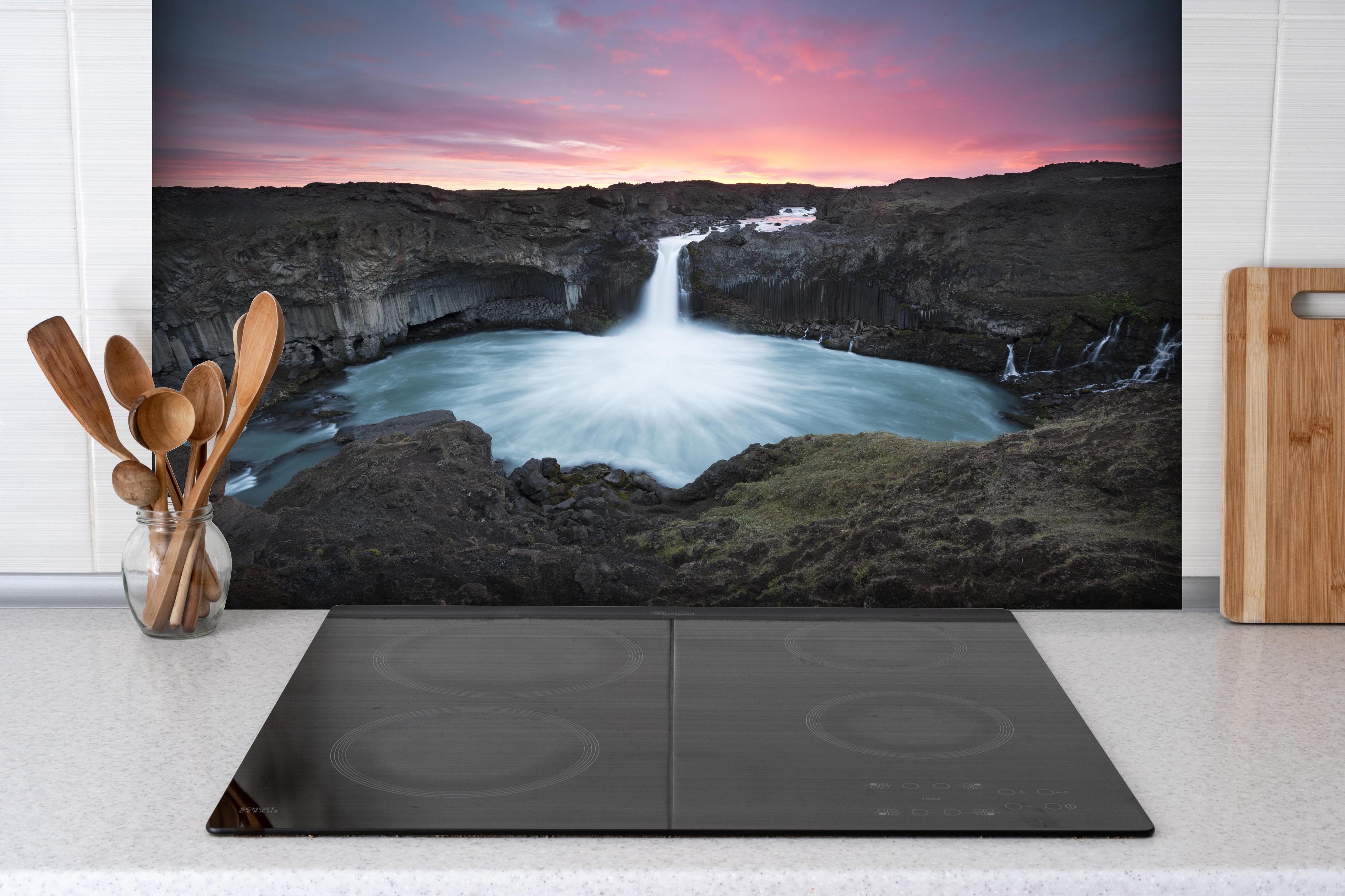 Spritzschutz - Island Wasserfall bei Sonnenuntergang hinter einem Cerankochfeld zwischen Holz-Kochutensilien
