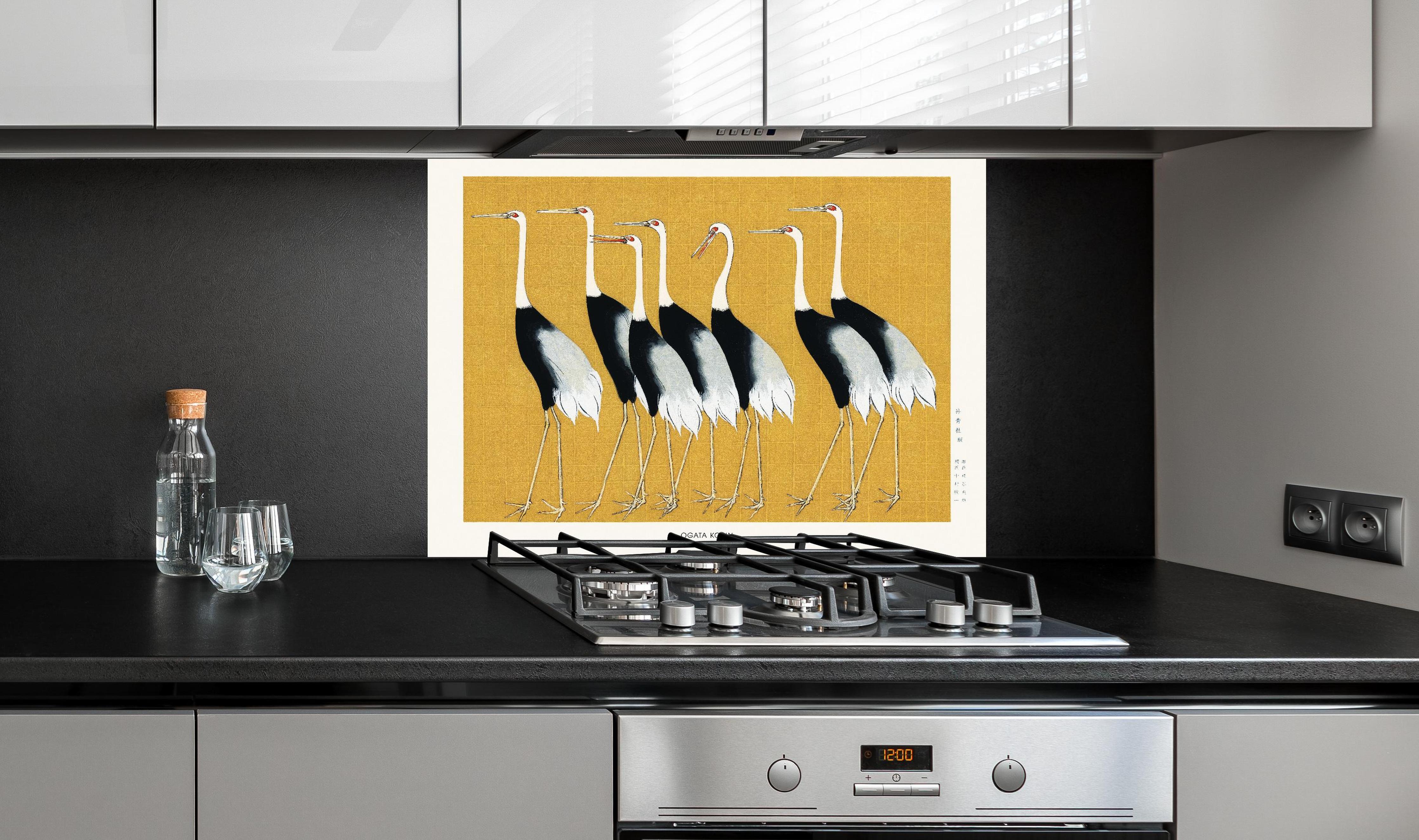 Spritzschutz - Japanischer Mandschurenkranich - Gold hinter einem Cerankochfeld zwischen Holz-Kochutensilien
