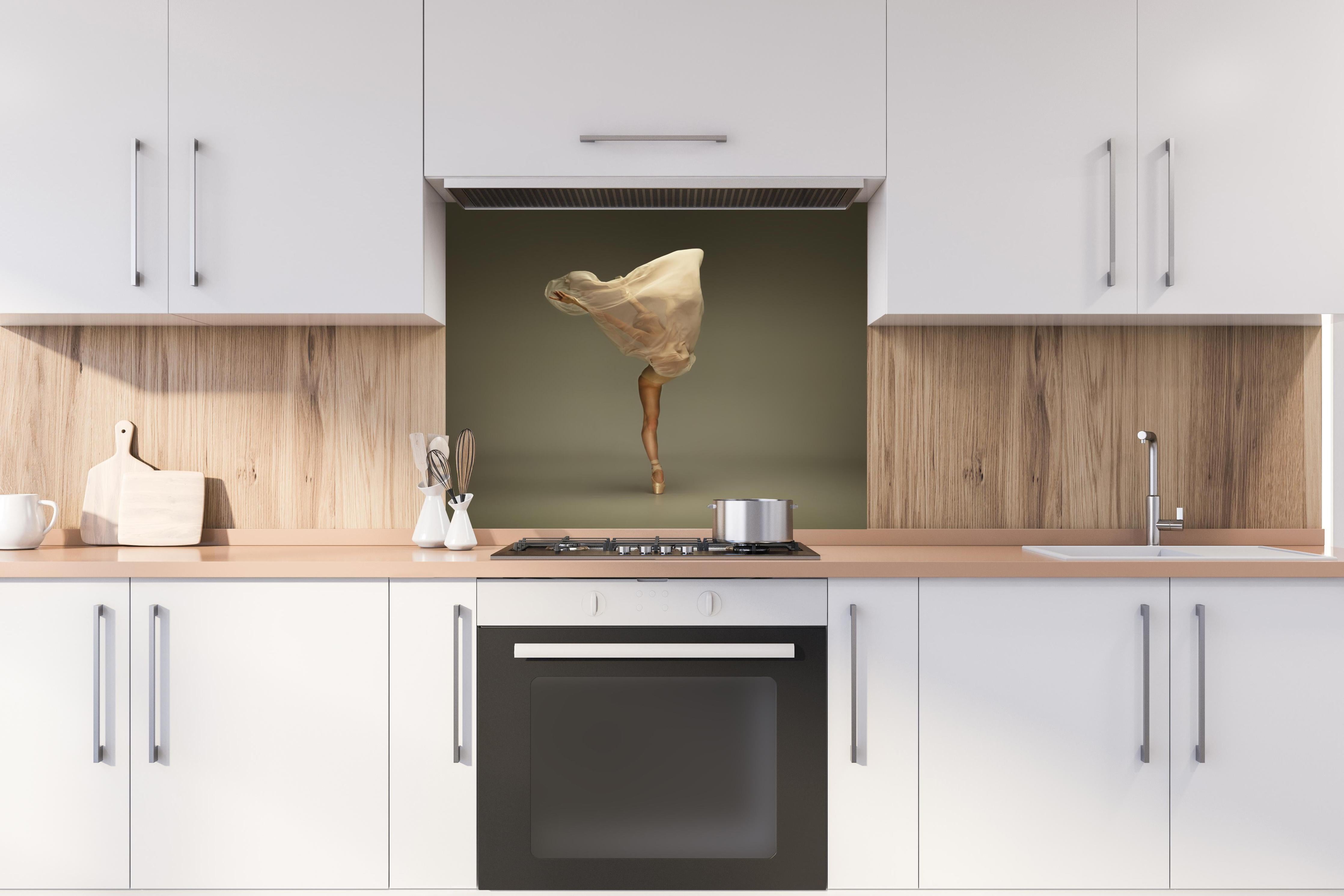 Spritzschutz - Junge Ballerina in grauem Studio  hinter einem Cerankochfeld zwischen Holz-Kochutensilien
