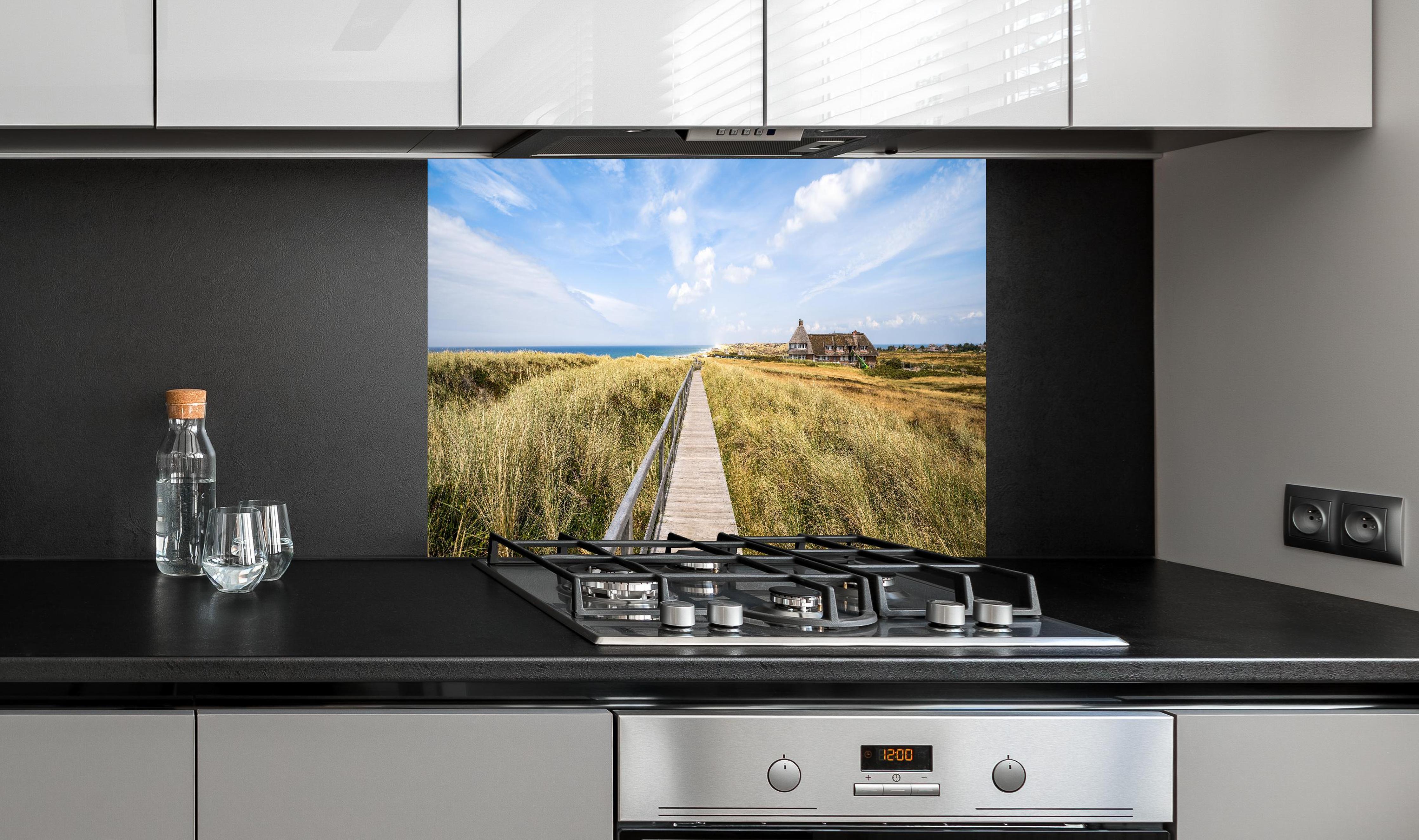 Spritzschutz - Kampen Landschaft hinter einem Cerankochfeld zwischen Holz-Kochutensilien
