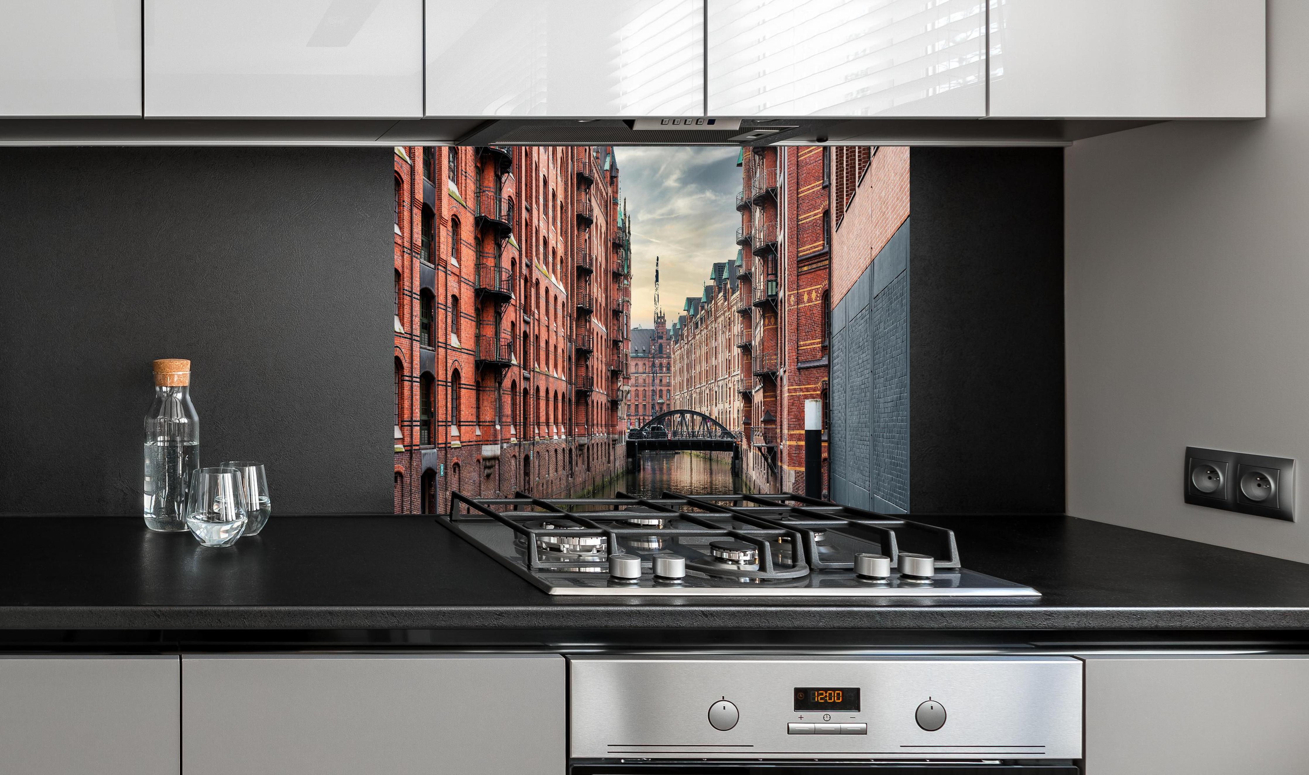 Spritzschutz - Kanal in der alten Speicherstadt hinter einem Cerankochfeld zwischen Holz-Kochutensilien
