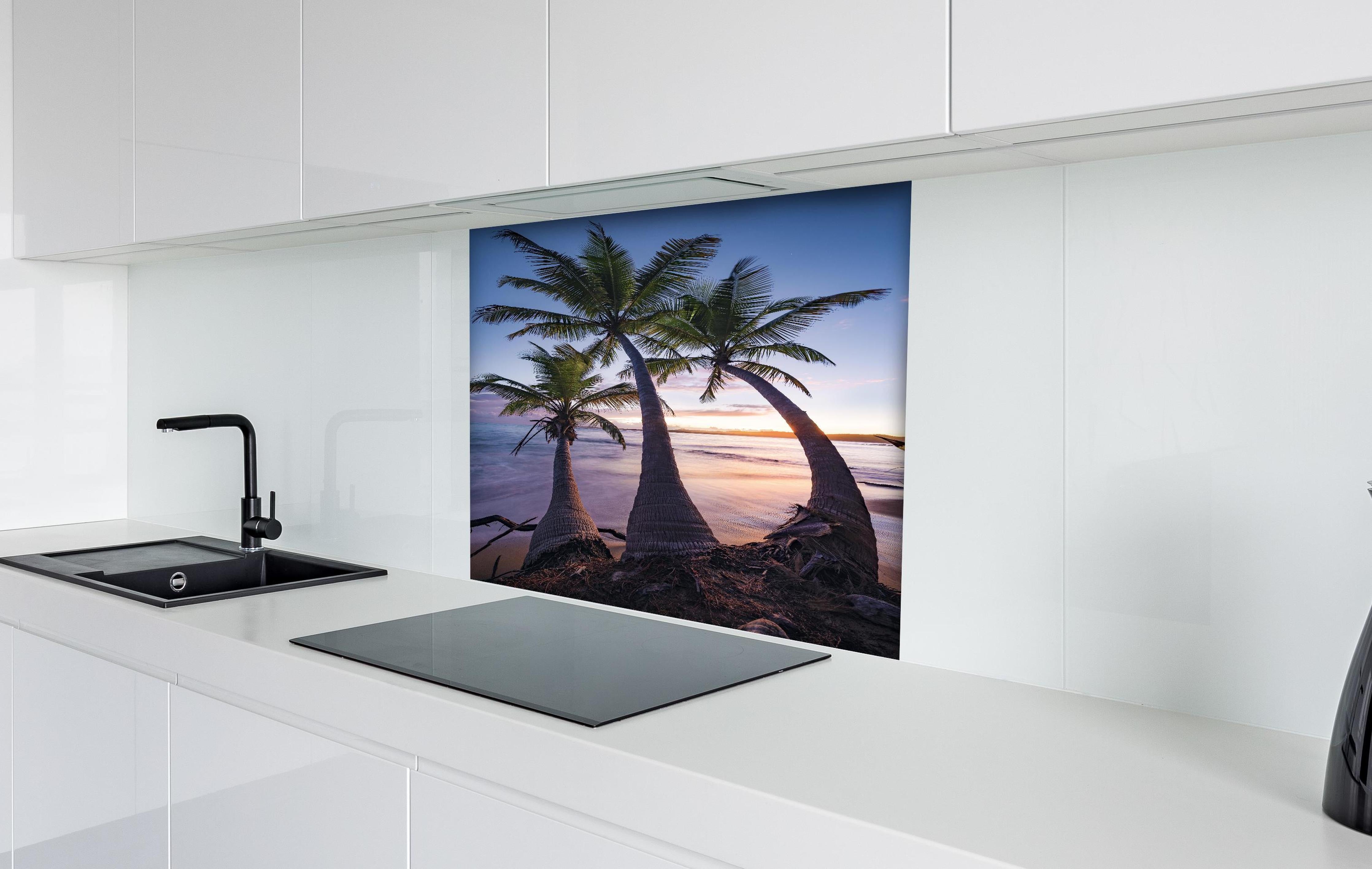 Spritzschutz - Karibik Palmenstrand bei Dämmerung hinter einem Cerankochfeld zwischen Holz-Kochutensilien
