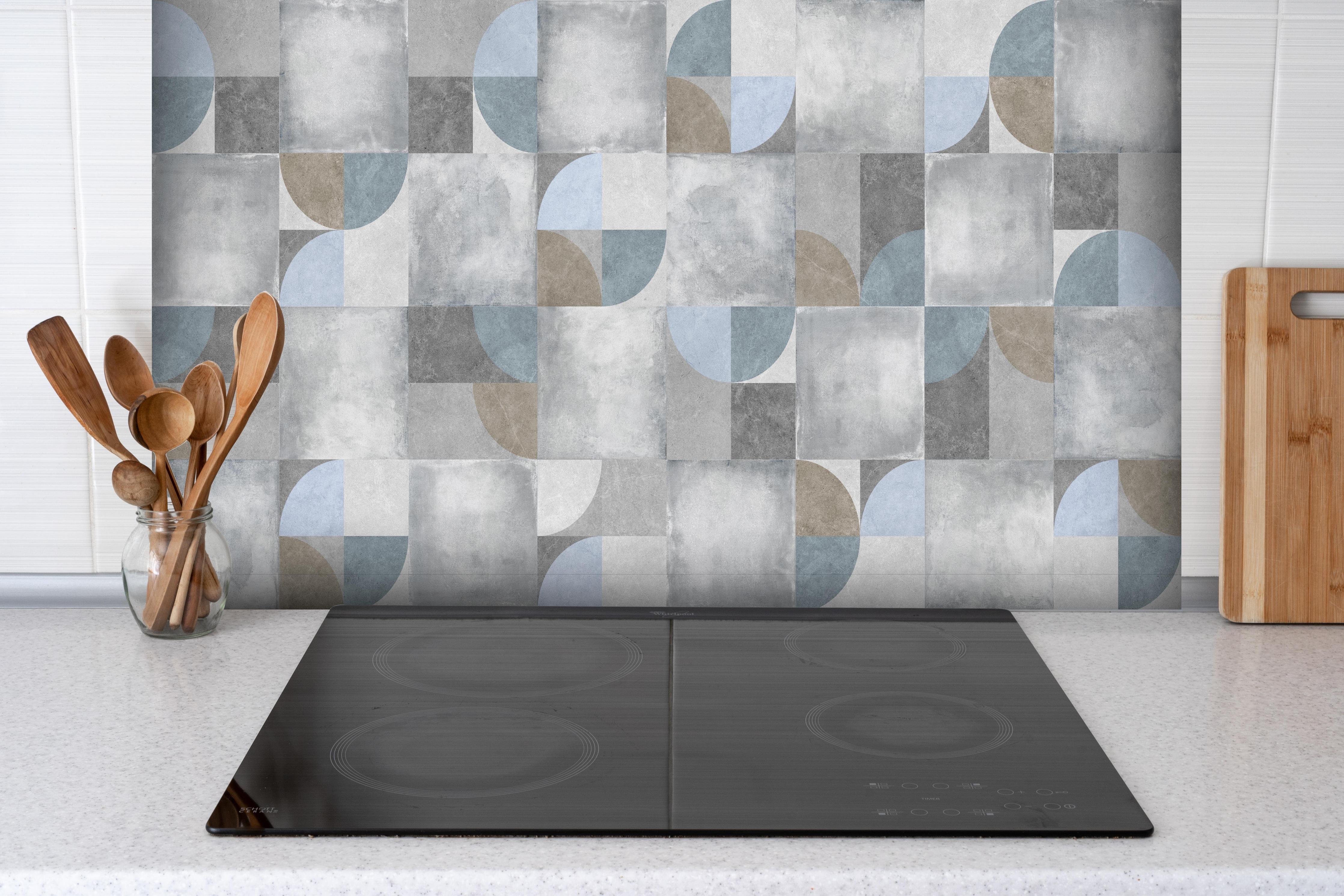Spritzschutz - Karierter Keramik Hintergrund hinter einem Cerankochfeld zwischen Holz-Kochutensilien
