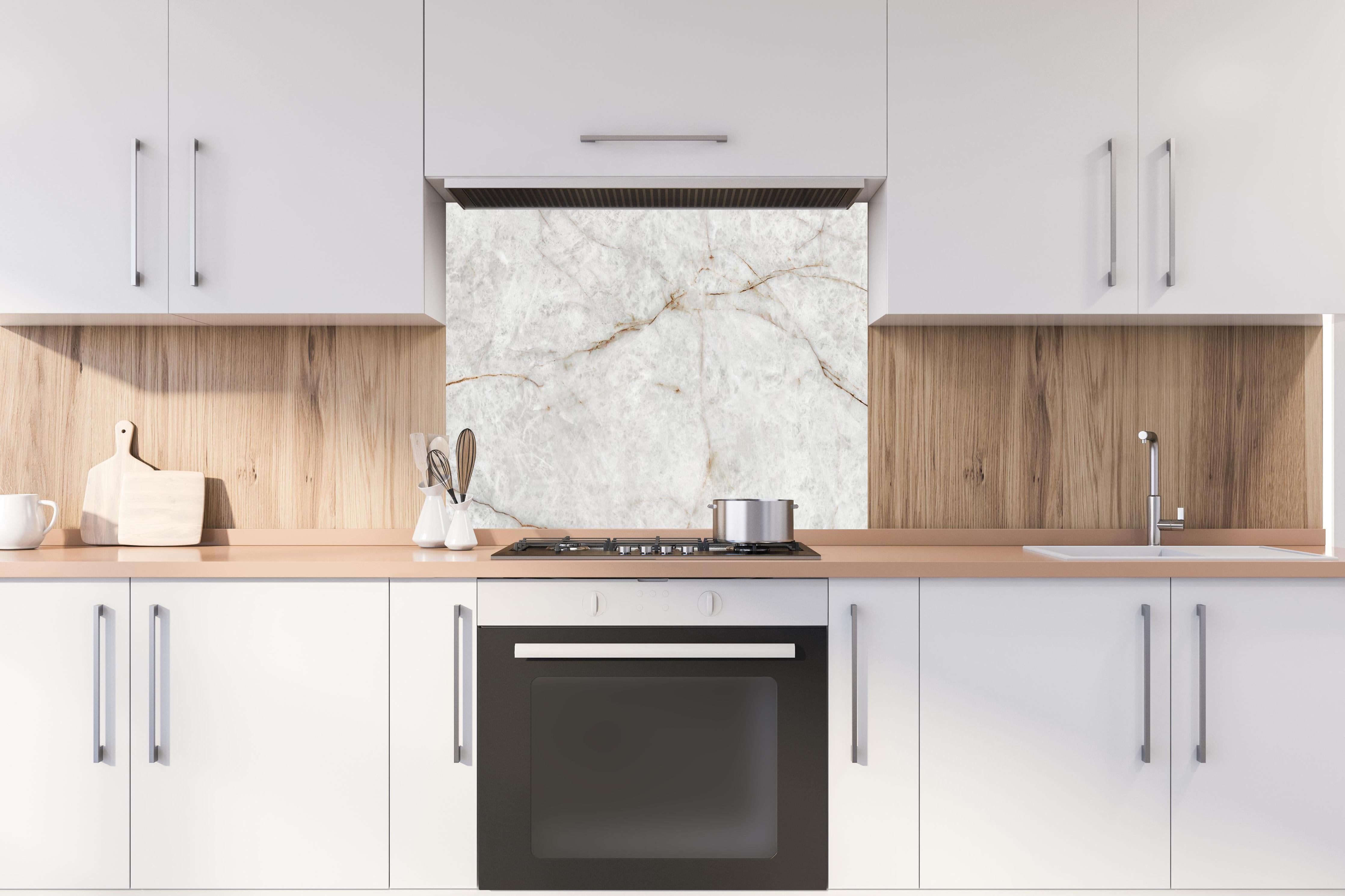 Spritzschutz - Keramik Marble Gold hinter einem Cerankochfeld zwischen Holz-Kochutensilien
