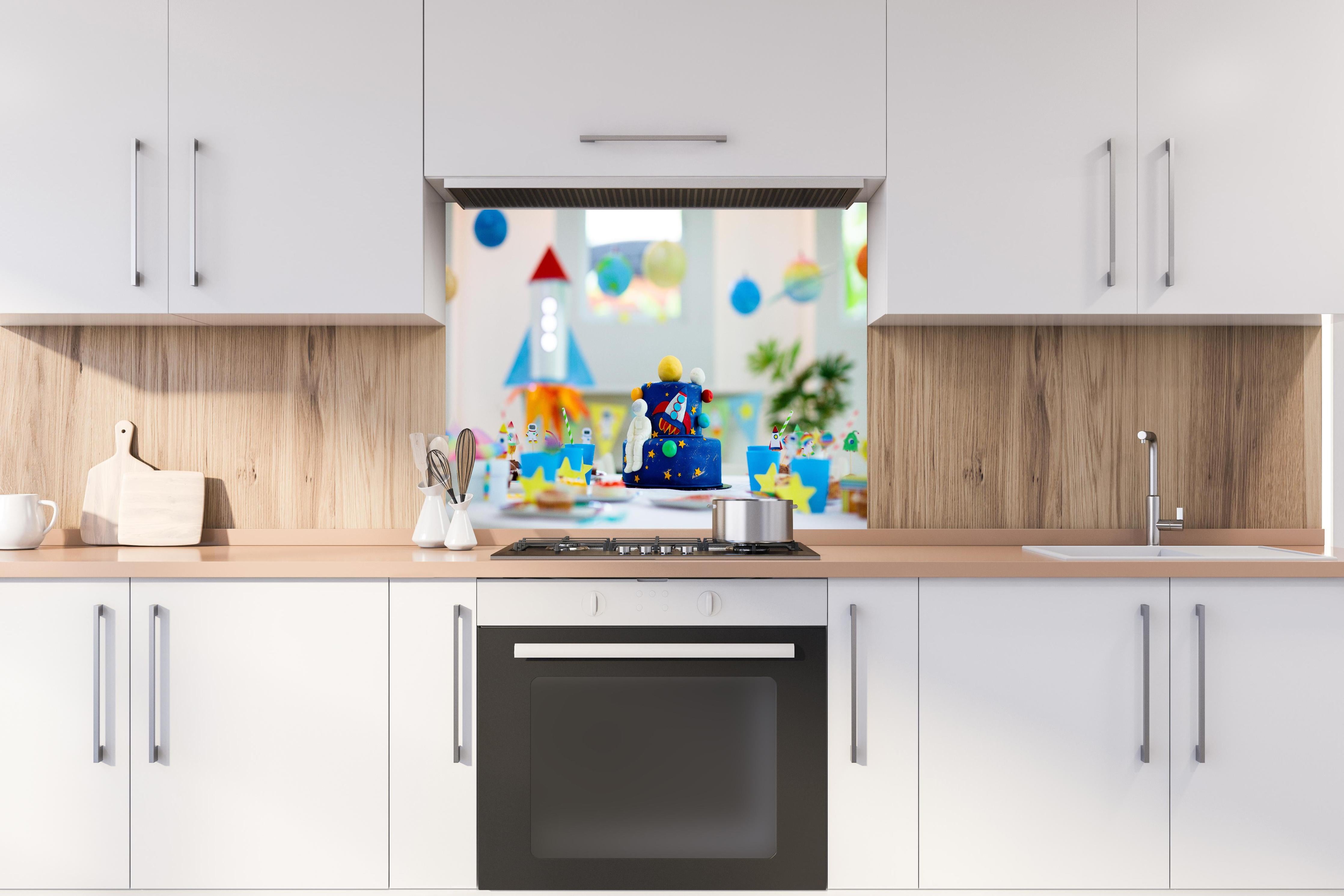 Spritzschutz - Kindergeburtstagsfeier zum Thema Weltraum mit Kuchen. hinter einem Cerankochfeld zwischen Holz-Kochutensilien
