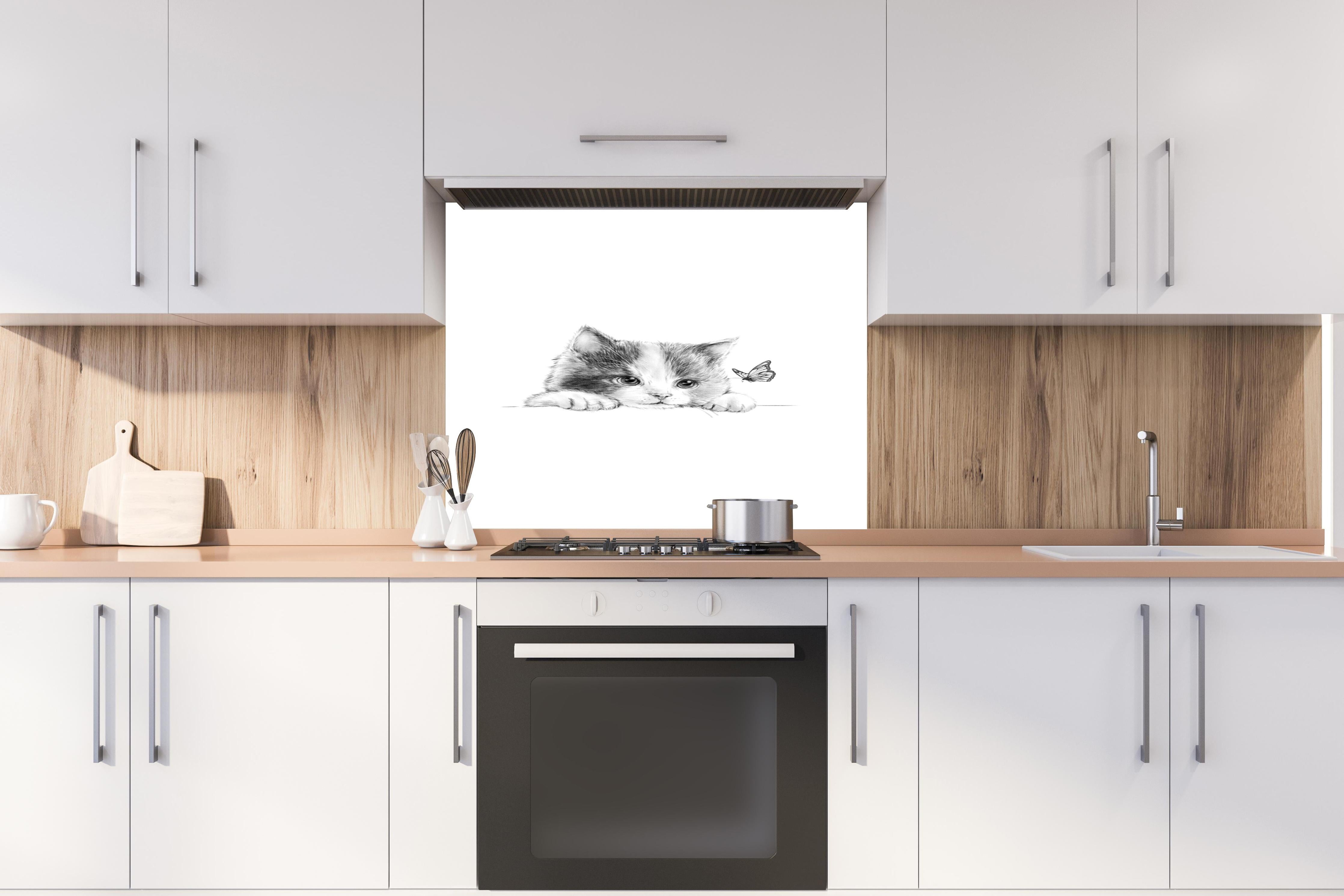 Spritzschutz - Kindermotiv einer Katze - schwarz-weiß hinter einem Cerankochfeld zwischen Holz-Kochutensilien
