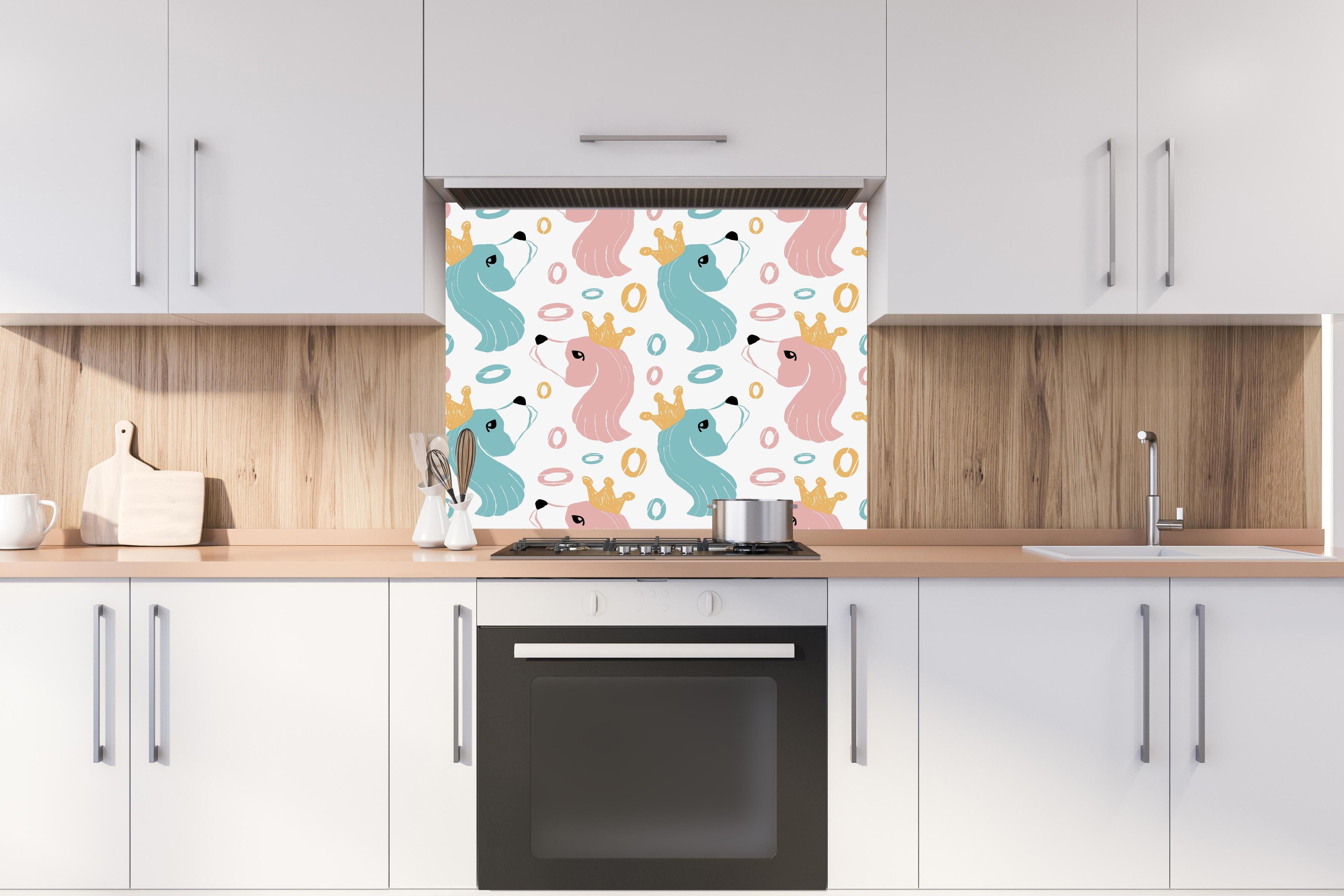 Spritzschutz - Kindliches Einhorn-Motiv mit Kronen hinter einem Cerankochfeld zwischen Holz-Kochutensilien
