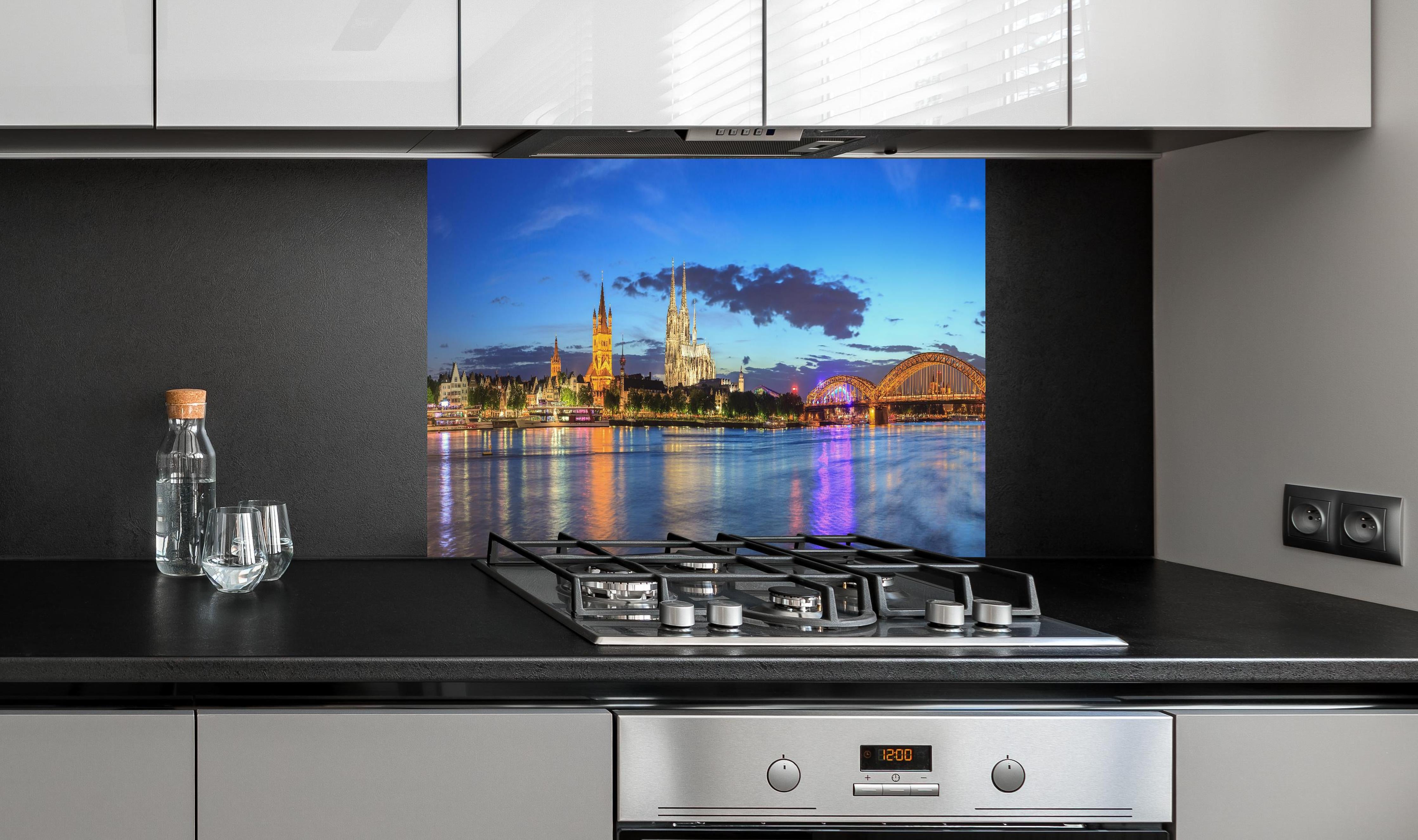 Spritzschutz - Kölner Skyline - Nachts hinter einem Cerankochfeld zwischen Holz-Kochutensilien
