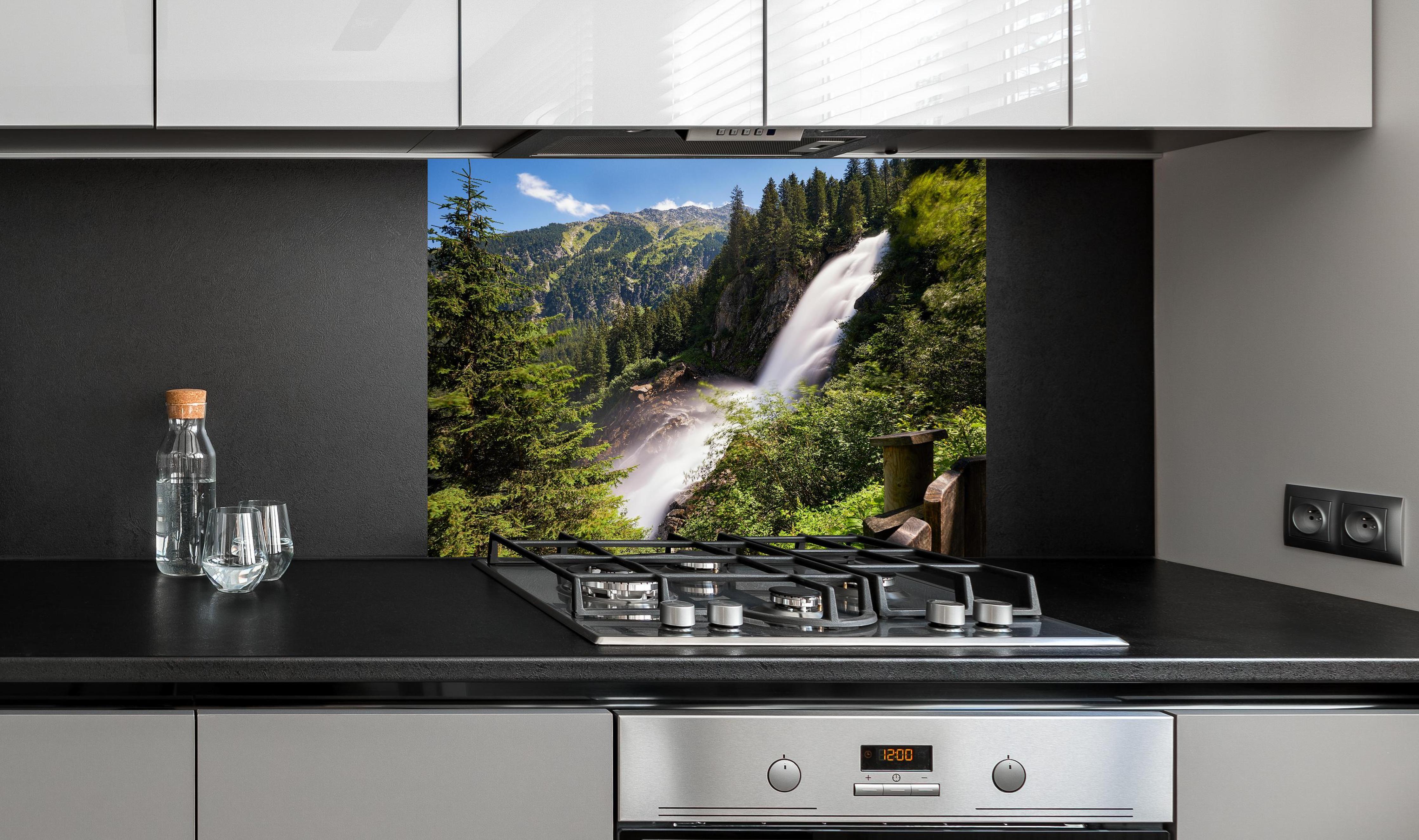 Spritzschutz - Krimmler Wasserfall hinter einem Cerankochfeld zwischen Holz-Kochutensilien
