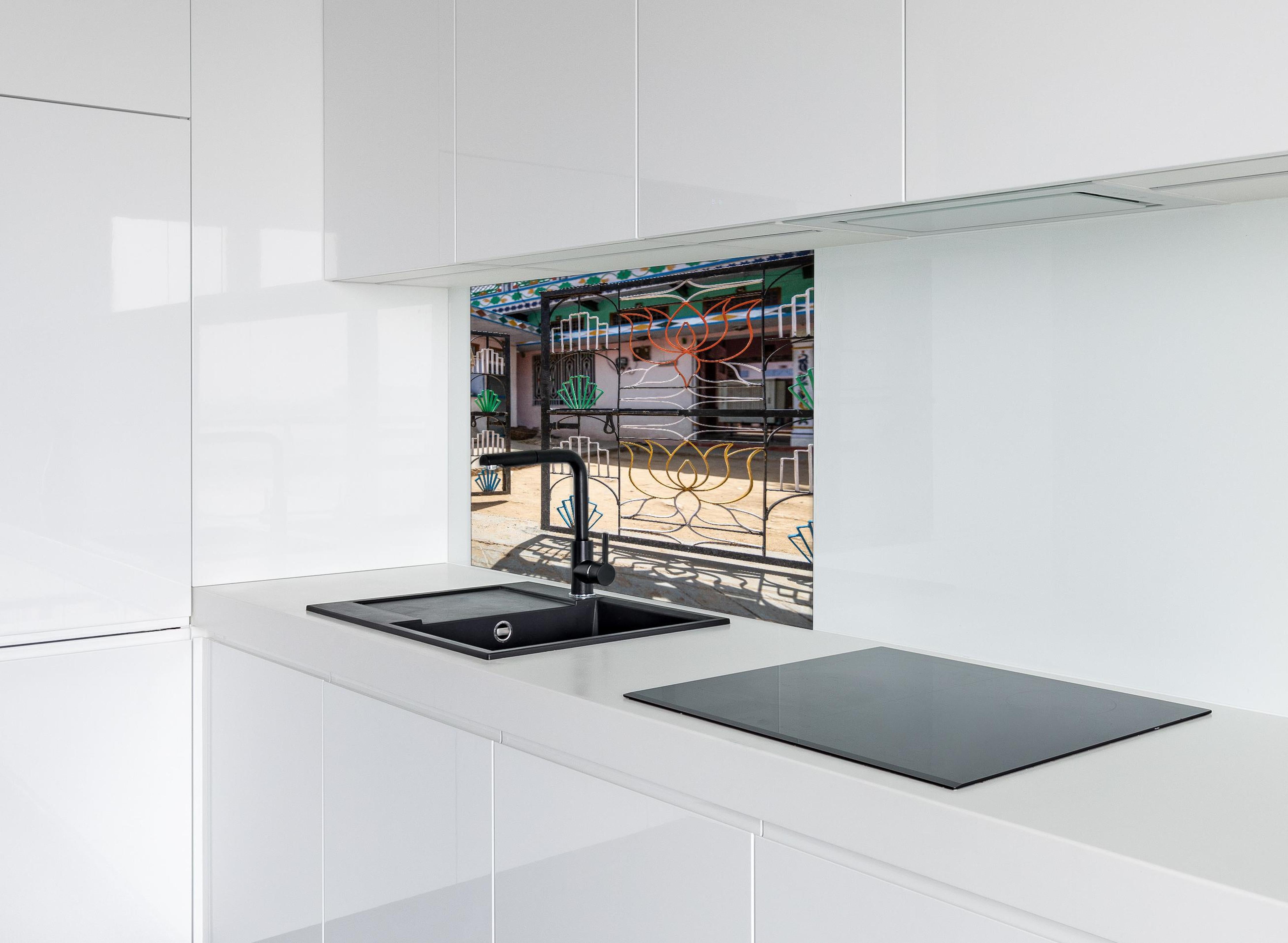 Spritzschutz - Künstlerisches Lotus-Tor gegen Hausfassade hinter einem Cerankochfeld zwischen Holz-Kochutensilien
