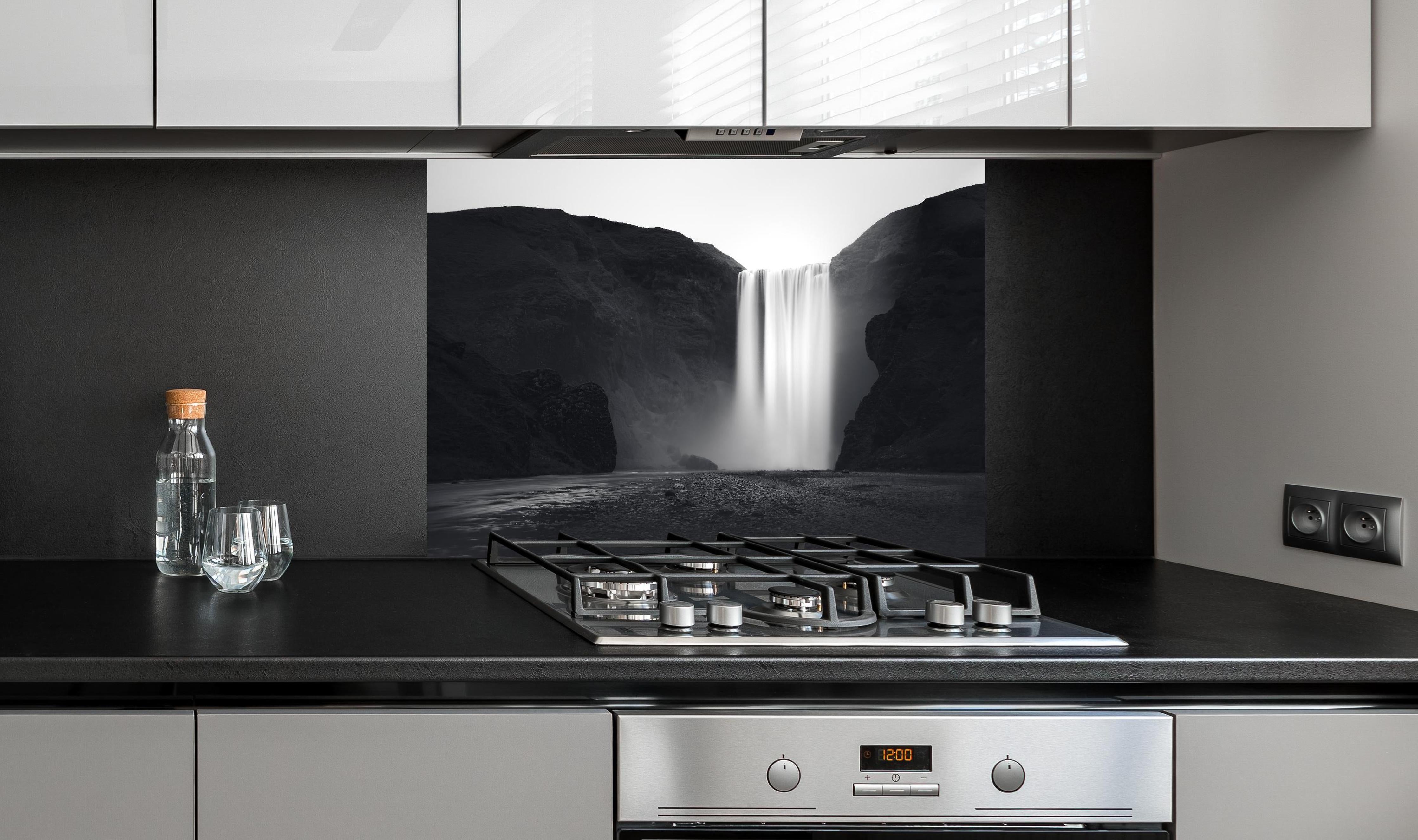 Spritzschutz - Kunstfotografie - Skogafoss Wasserfall, Island hinter einem Cerankochfeld zwischen Holz-Kochutensilien
