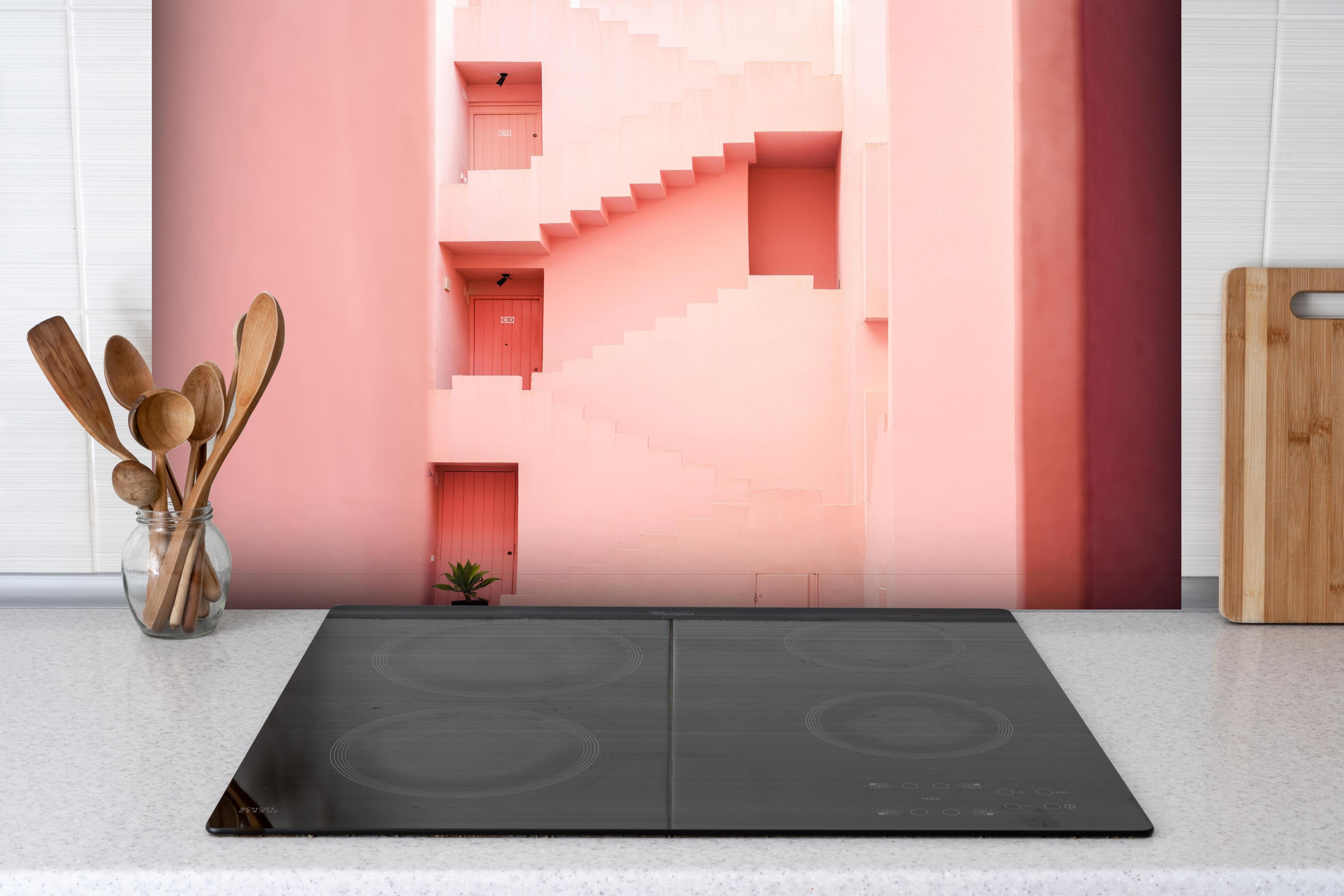 Spritzschutz - La Muralla Roja in Pink, Spanisches Design hinter einem Cerankochfeld zwischen Holz-Kochutensilien
