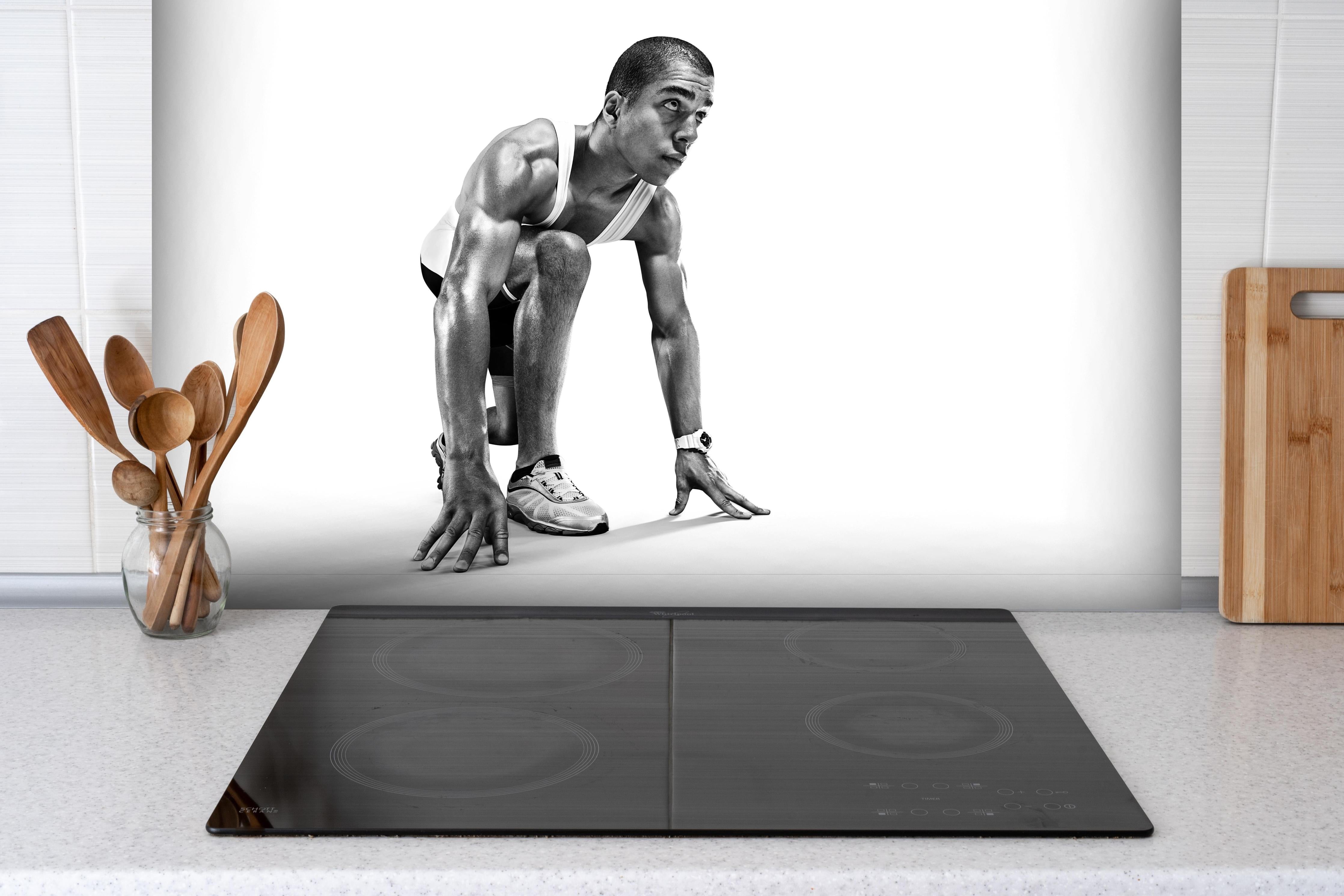 Spritzschutz - Läufer bereitet sich vor hinter einem Cerankochfeld zwischen Holz-Kochutensilien
