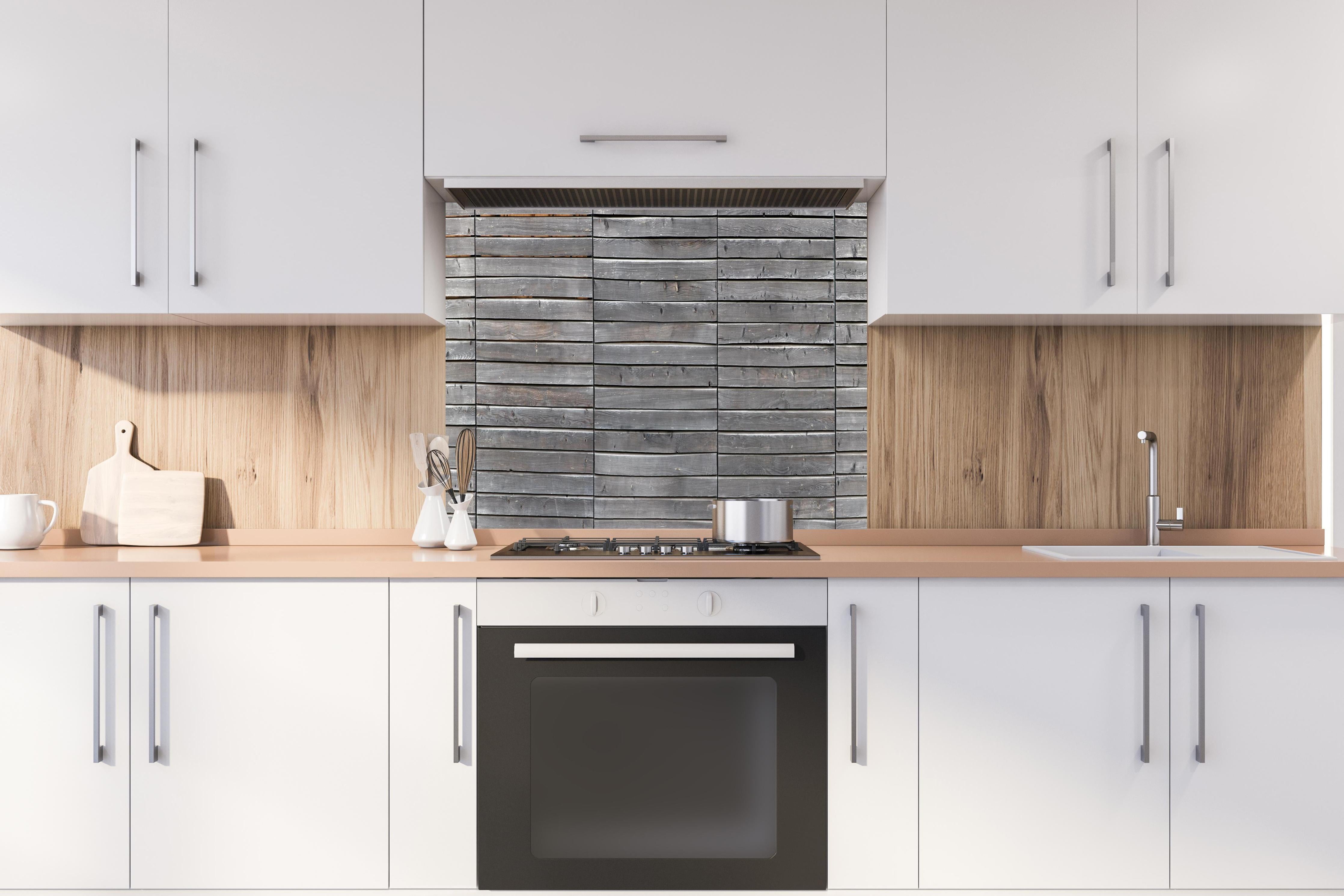 Spritzschutz - Langer grauer Holzzaun hinter einem Cerankochfeld zwischen Holz-Kochutensilien
