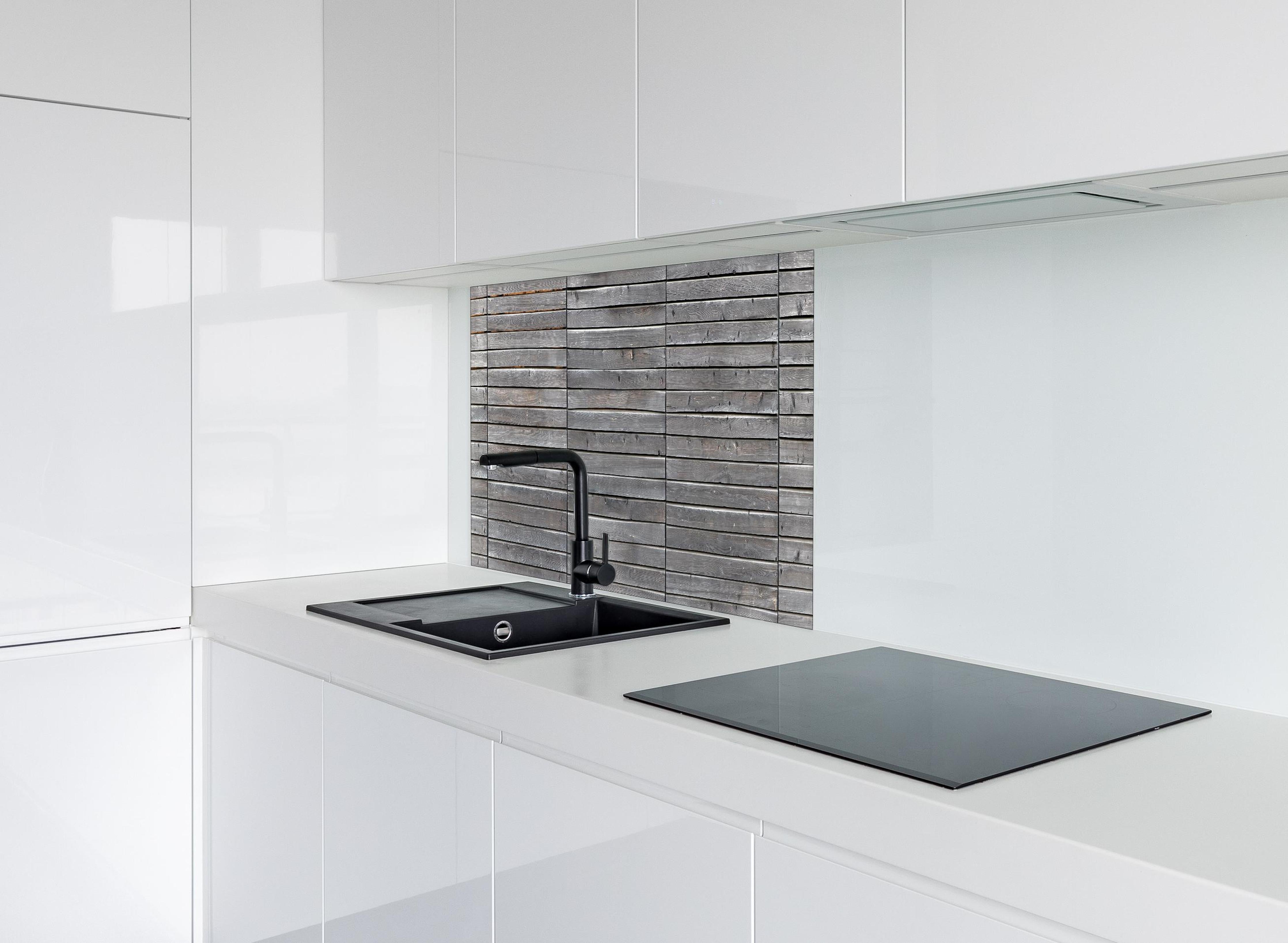 Spritzschutz - Langer grauer Holzzaun hinter einem Cerankochfeld zwischen Holz-Kochutensilien
