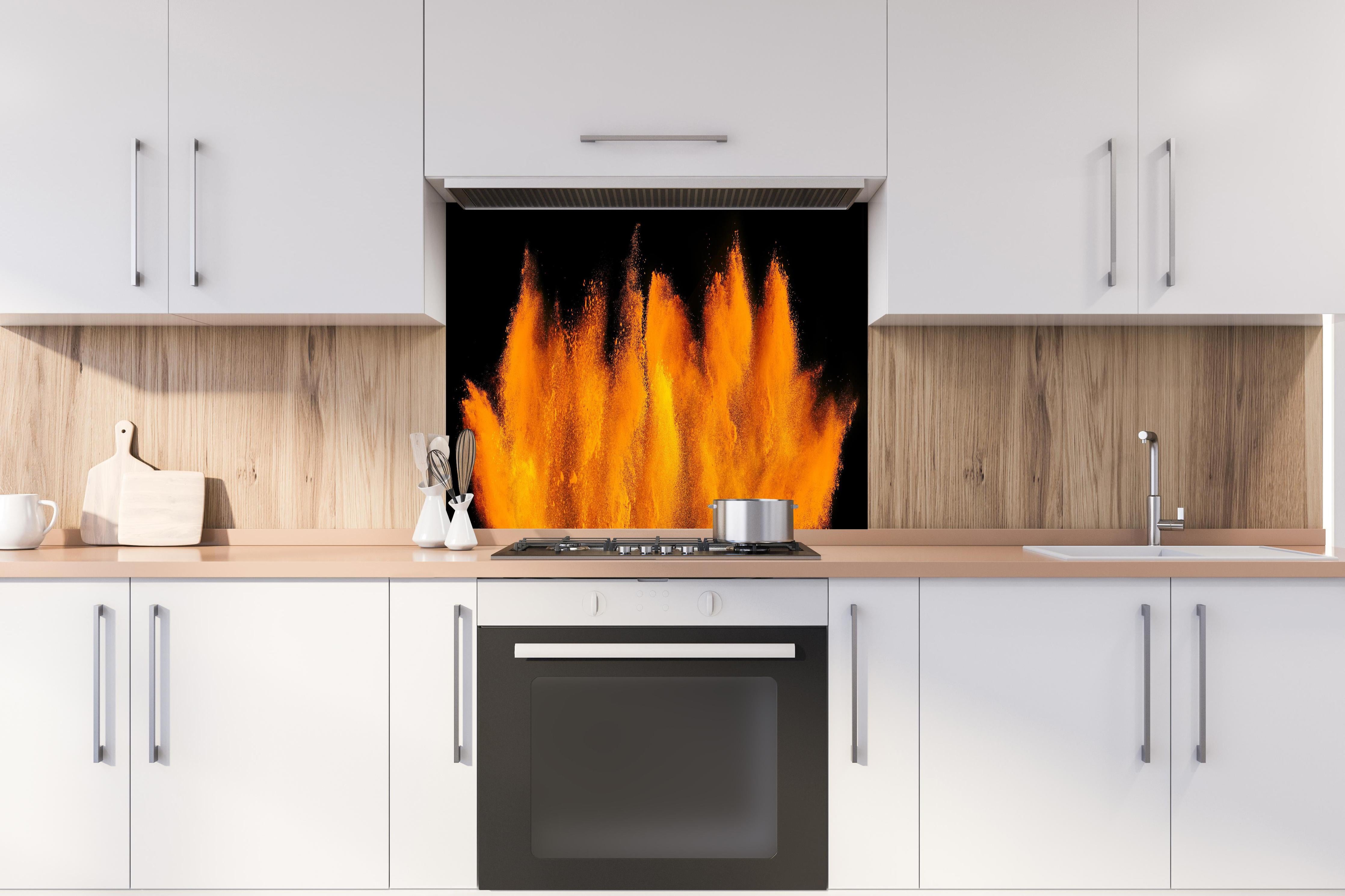 Spritzschutz - Lebendige Holi Farbexplosion auf Schwarz hinter einem Cerankochfeld zwischen Holz-Kochutensilien
