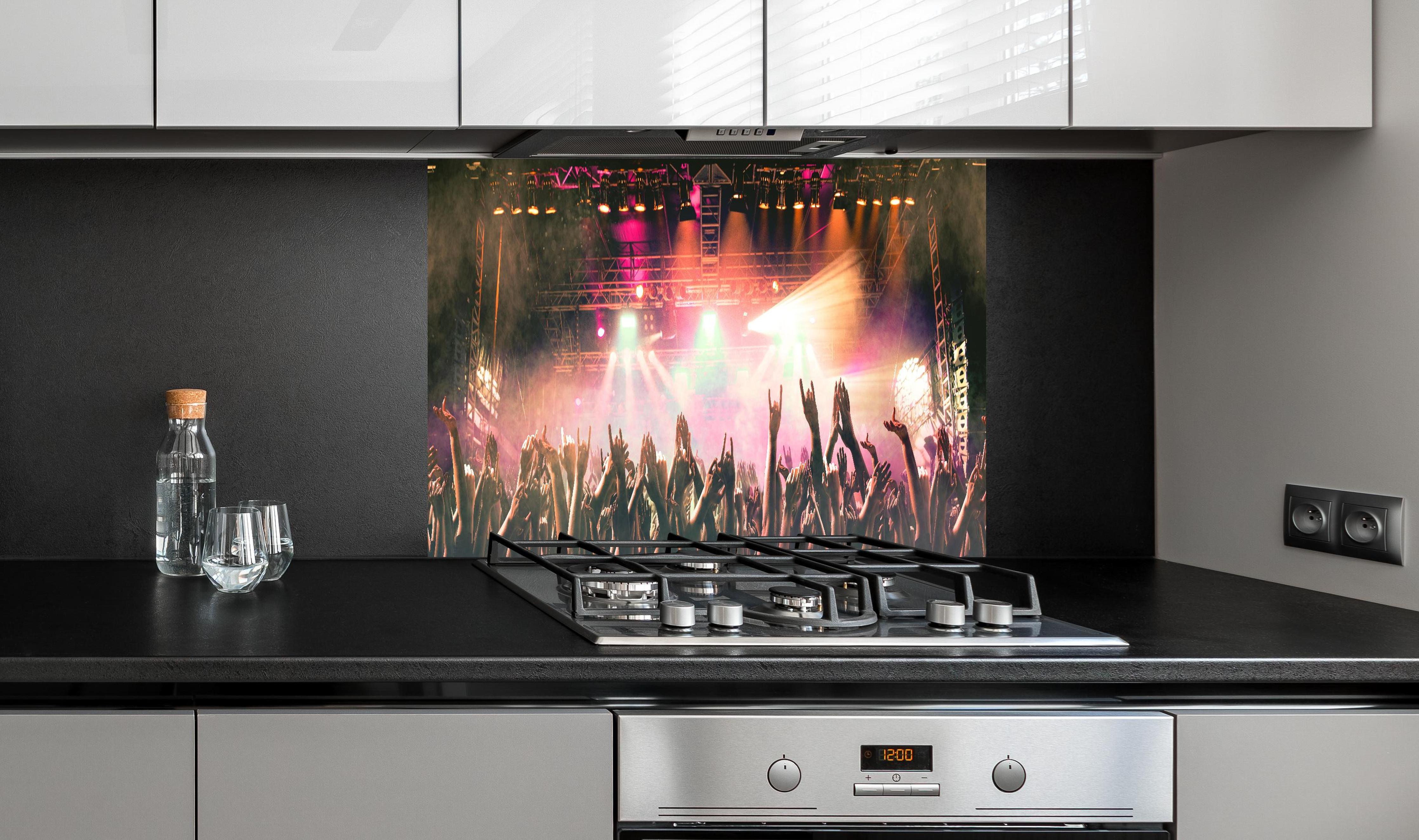 Spritzschutz - Lebhaftes Live-Musikkonzert mit Publikum hinter einem Cerankochfeld zwischen Holz-Kochutensilien
