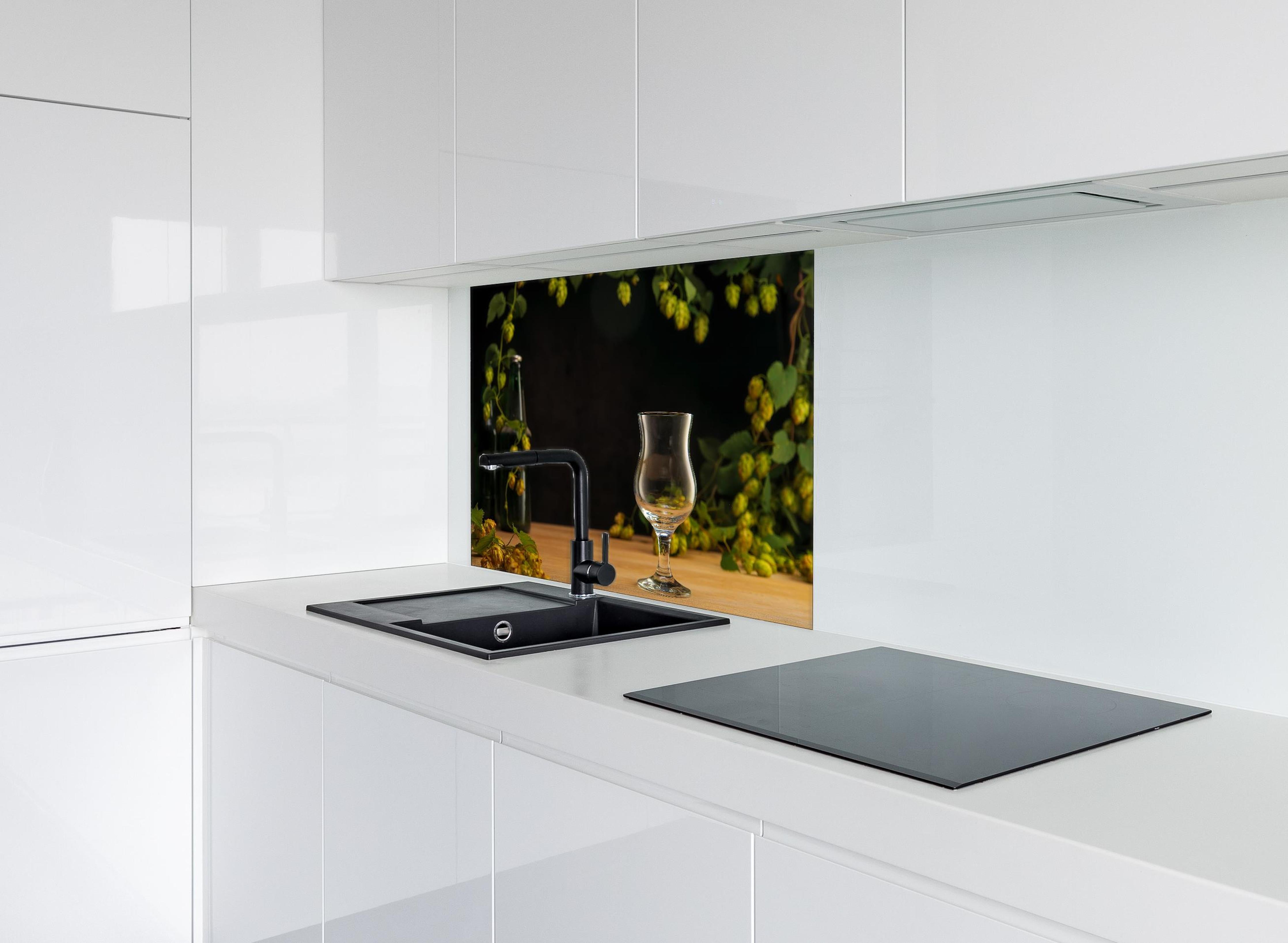 Spritzschutz - Leeres Tulpenglas auf Holztisch hinter einem Cerankochfeld zwischen Holz-Kochutensilien
