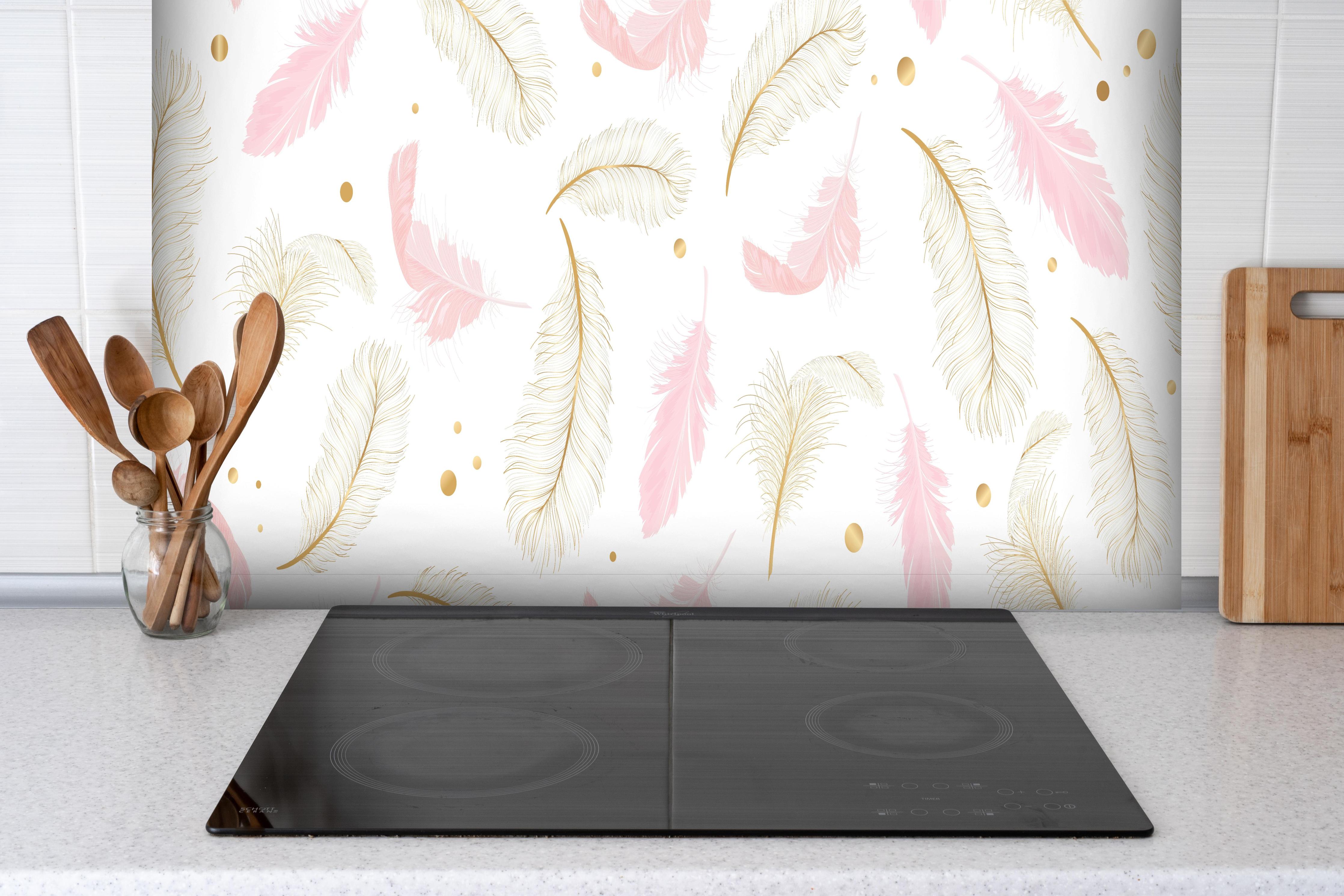 Spritzschutz - Leichtes Federmuster mit goldenen Akzenten hinter einem Cerankochfeld zwischen Holz-Kochutensilien

