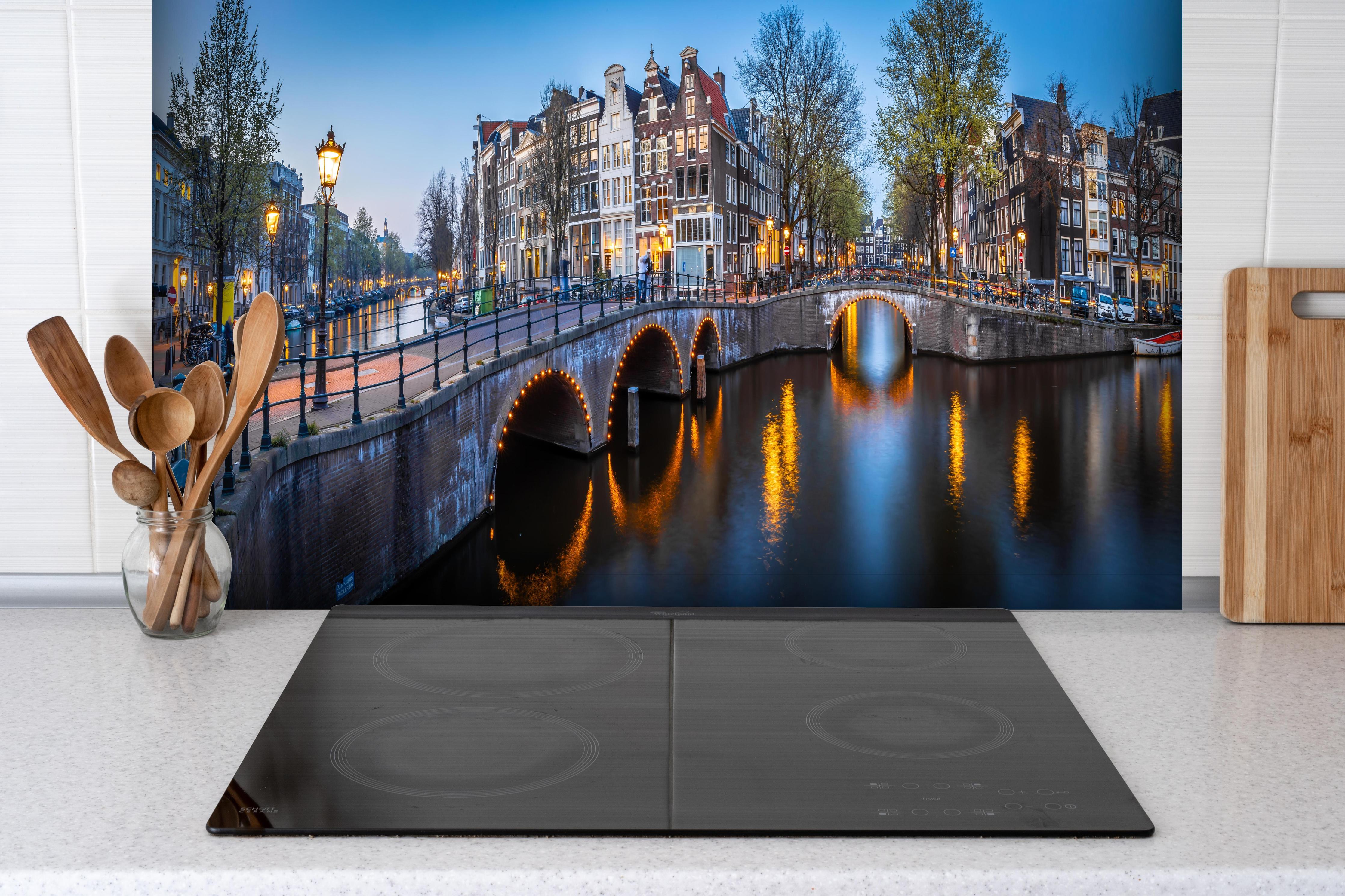 Spritzschutz - Leidsegracht-Brücke - Amsterdam hinter einem Cerankochfeld zwischen Holz-Kochutensilien
