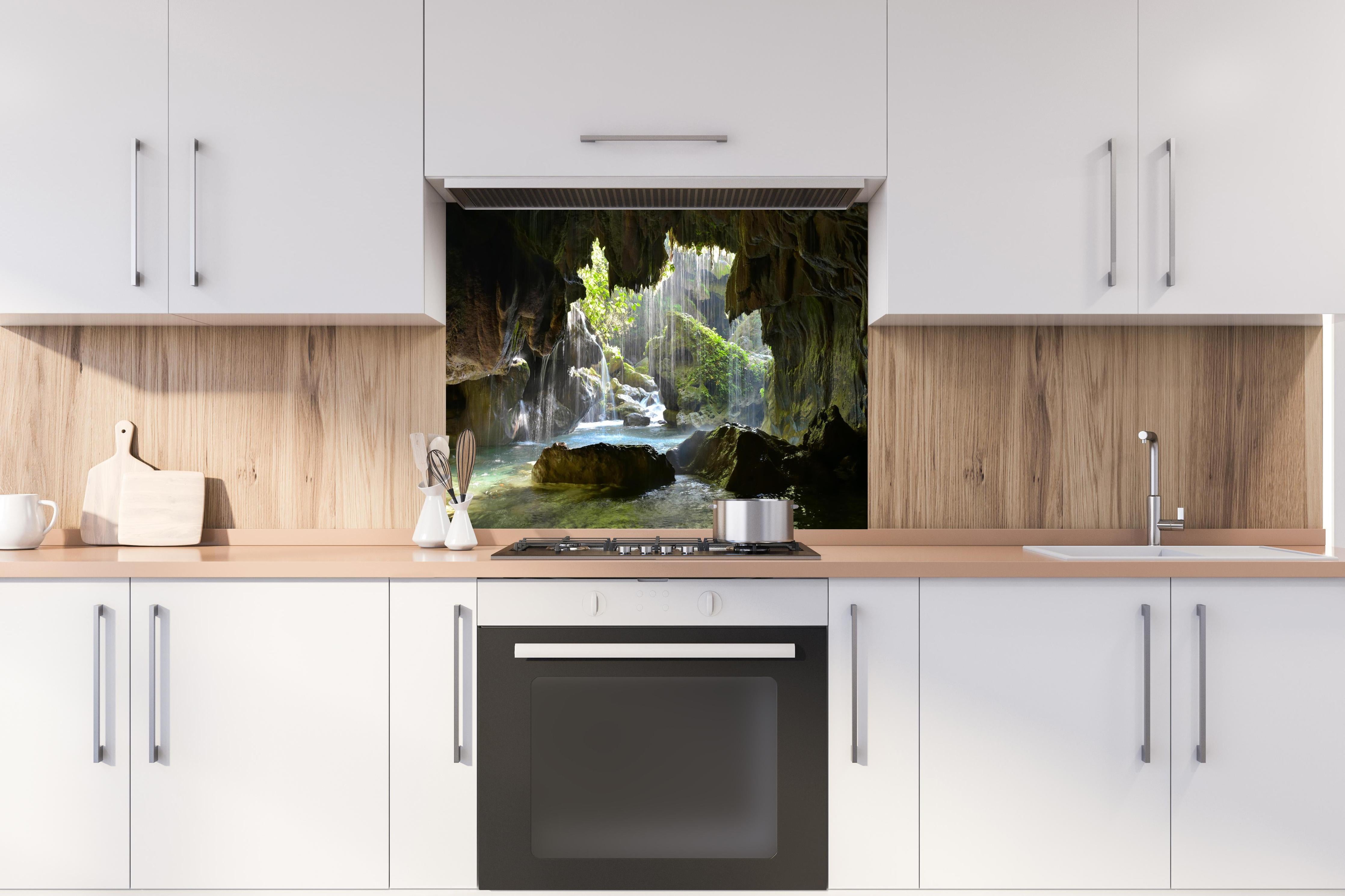 Spritzschutz - Lichtdurchflutete Grüne Höhlenlandschaft hinter einem Cerankochfeld zwischen Holz-Kochutensilien
