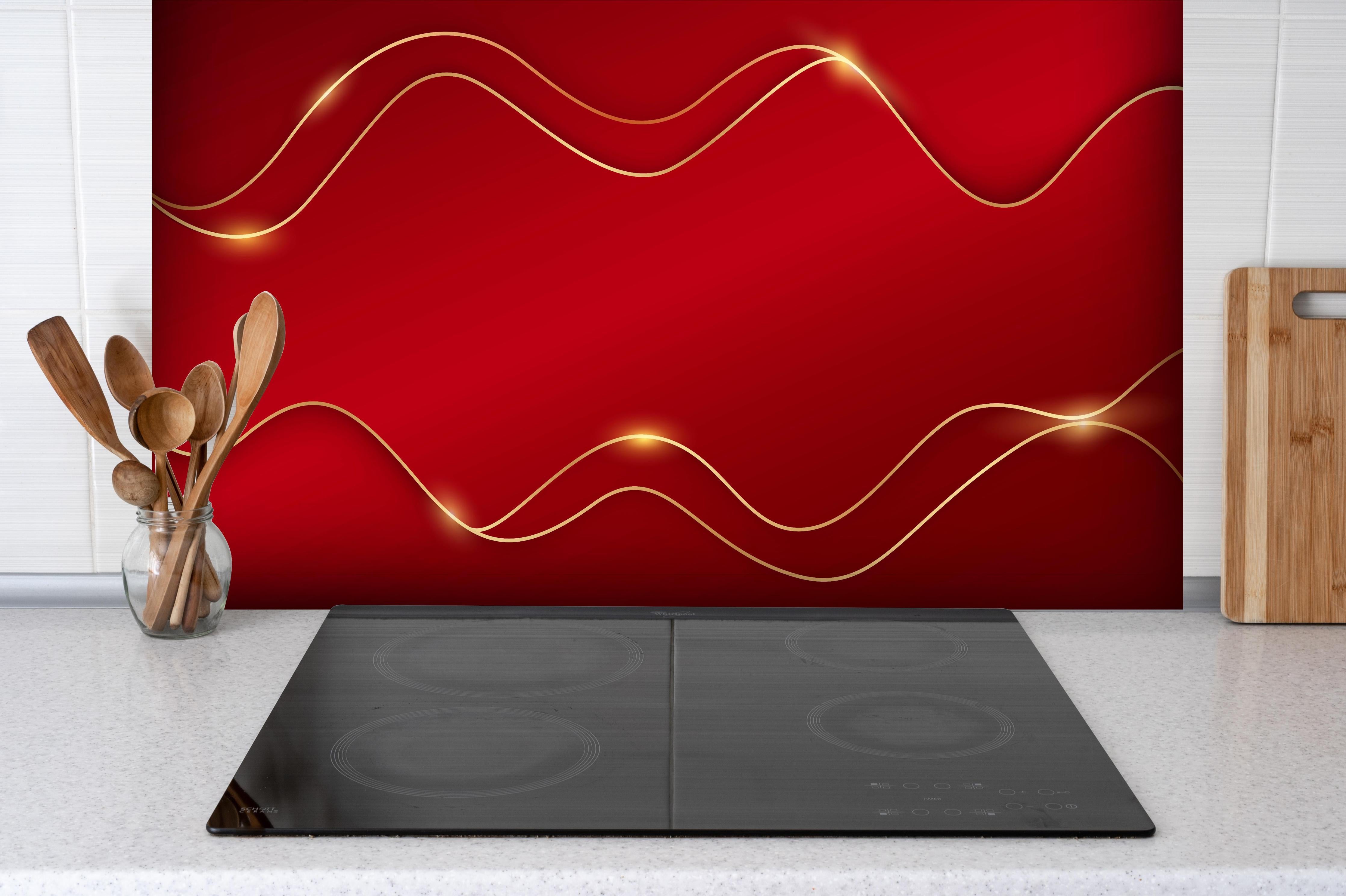 Spritzschutz - Luxuriöses Rot mit goldenen Akzenten hinter einem Cerankochfeld zwischen Holz-Kochutensilien
