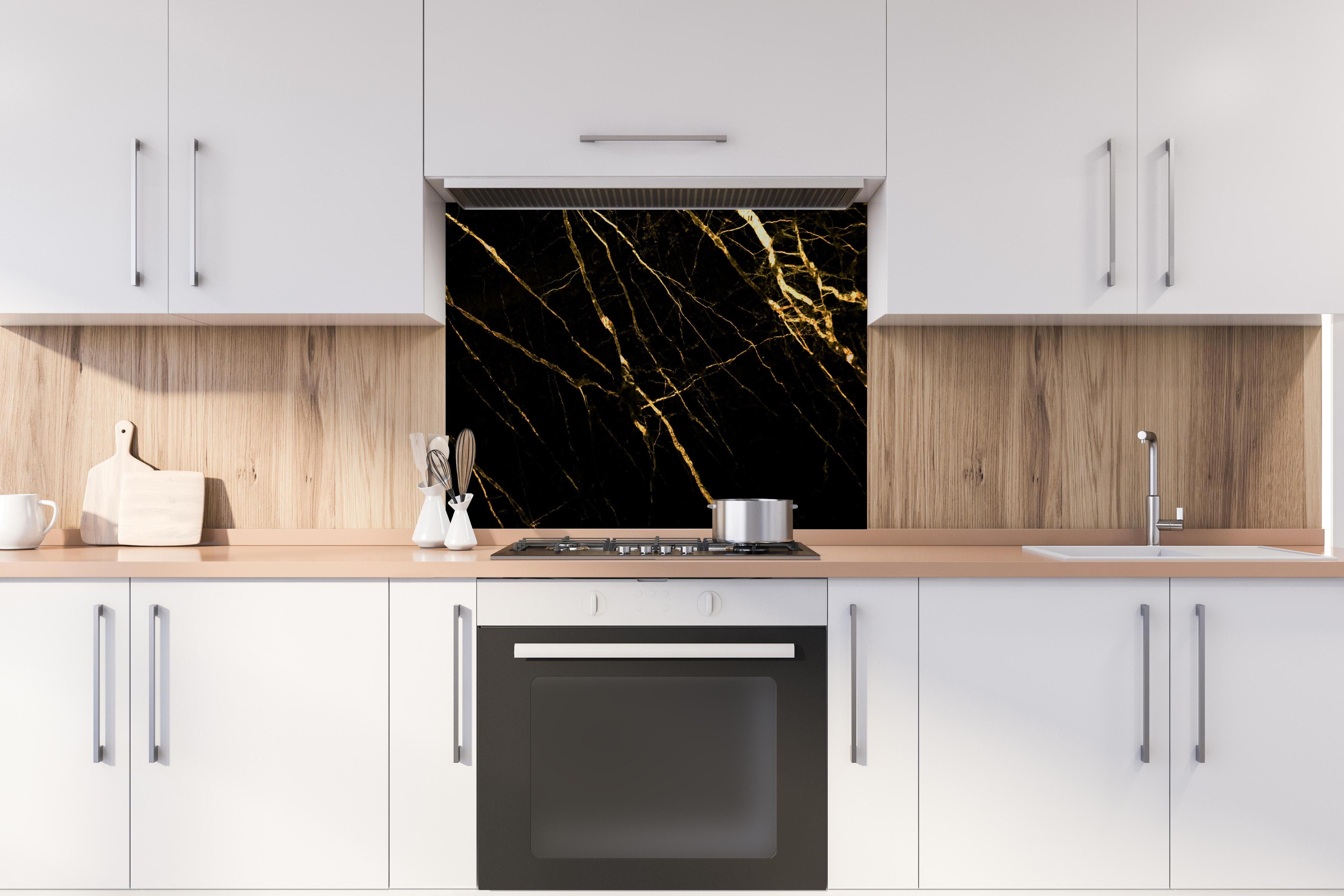 Spritzschutz - Luxus Goldmarmortextur  hinter einem Cerankochfeld zwischen Holz-Kochutensilien
