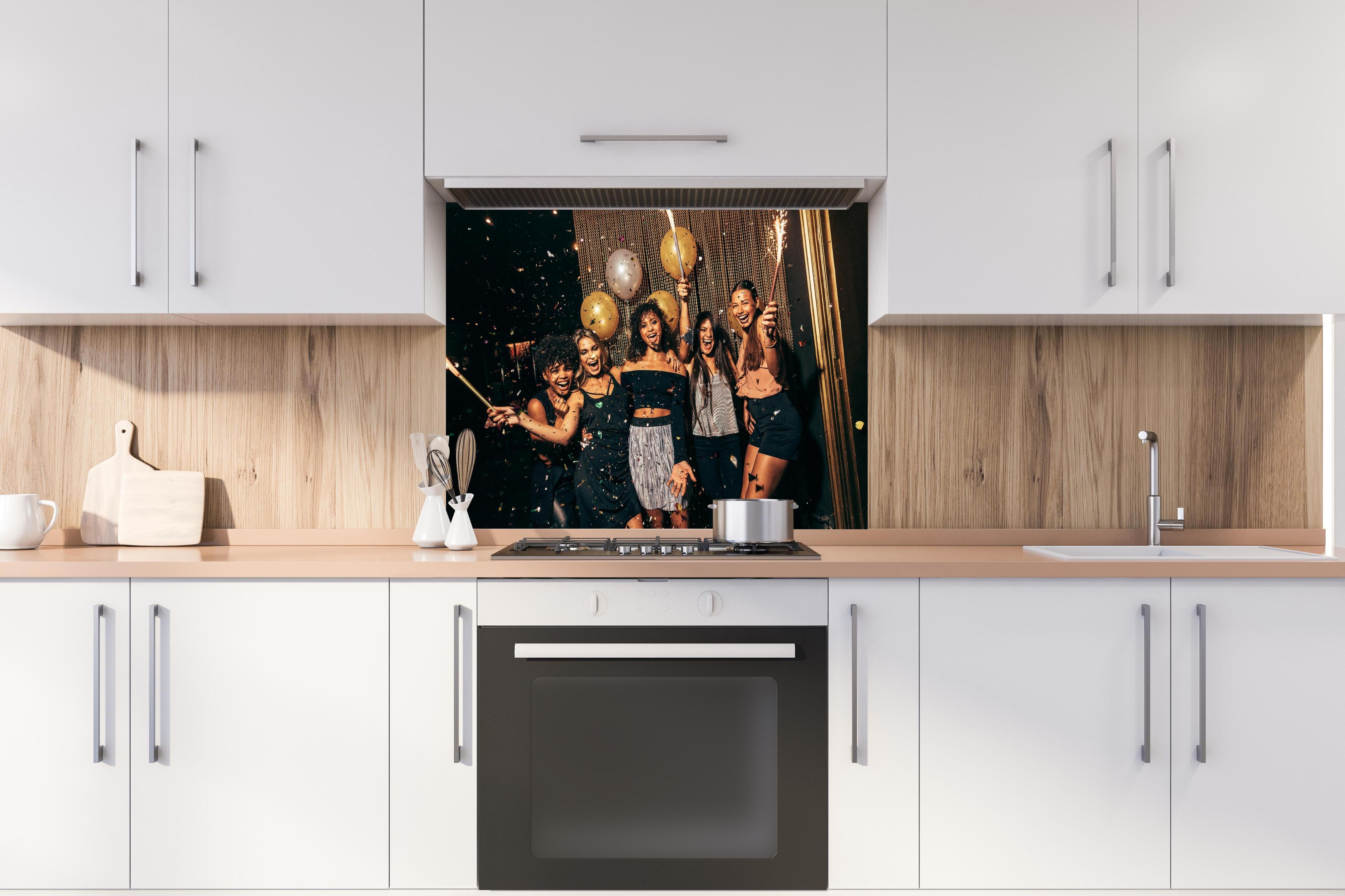 Spritzschutz - Mädchen im Nachtclub haben eine tolle Zeit hinter einem Cerankochfeld zwischen Holz-Kochutensilien
