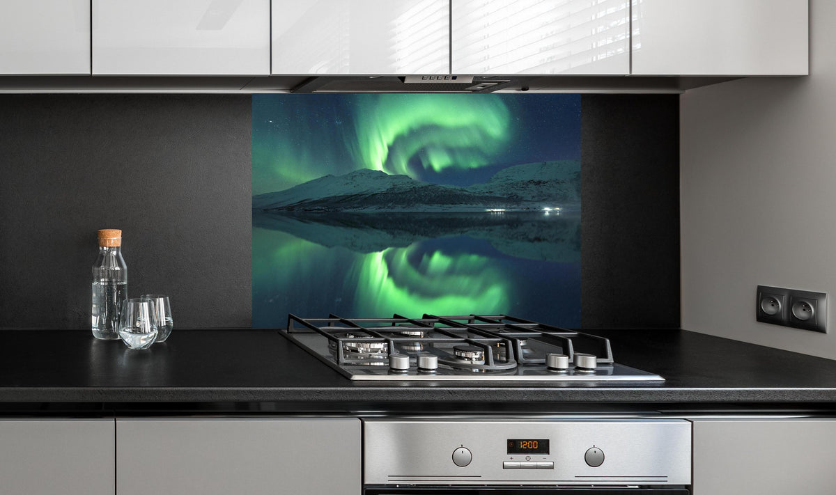 Spritzschutz - Magisches Nordlicht Spiegelbild Norwegen hinter einem Cerankochfeld zwischen Holz-Kochutensilien
