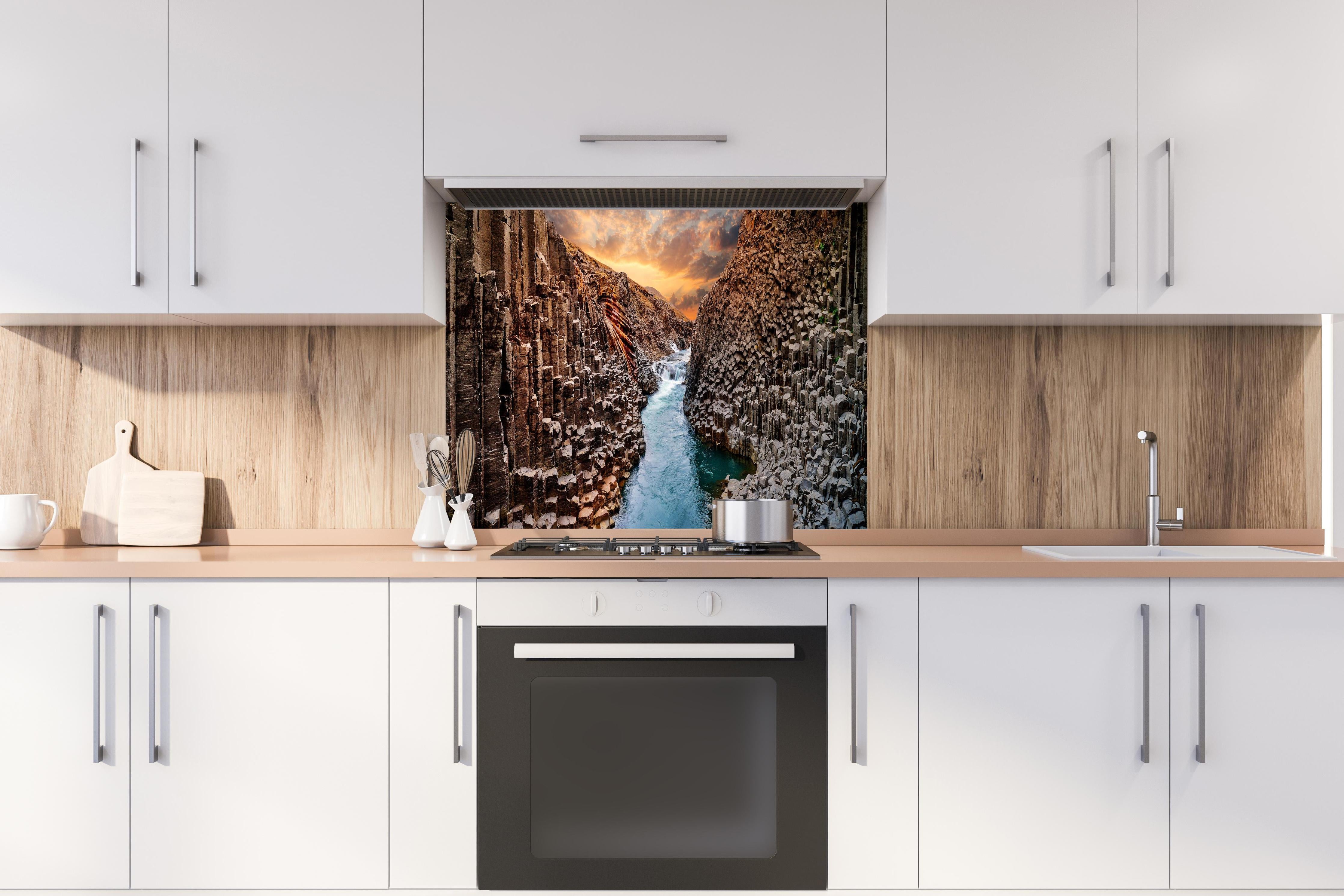 Spritzschutz - Majestätische Basalt-Schlucht Island Sonnenuntergang hinter einem Cerankochfeld zwischen Holz-Kochutensilien
