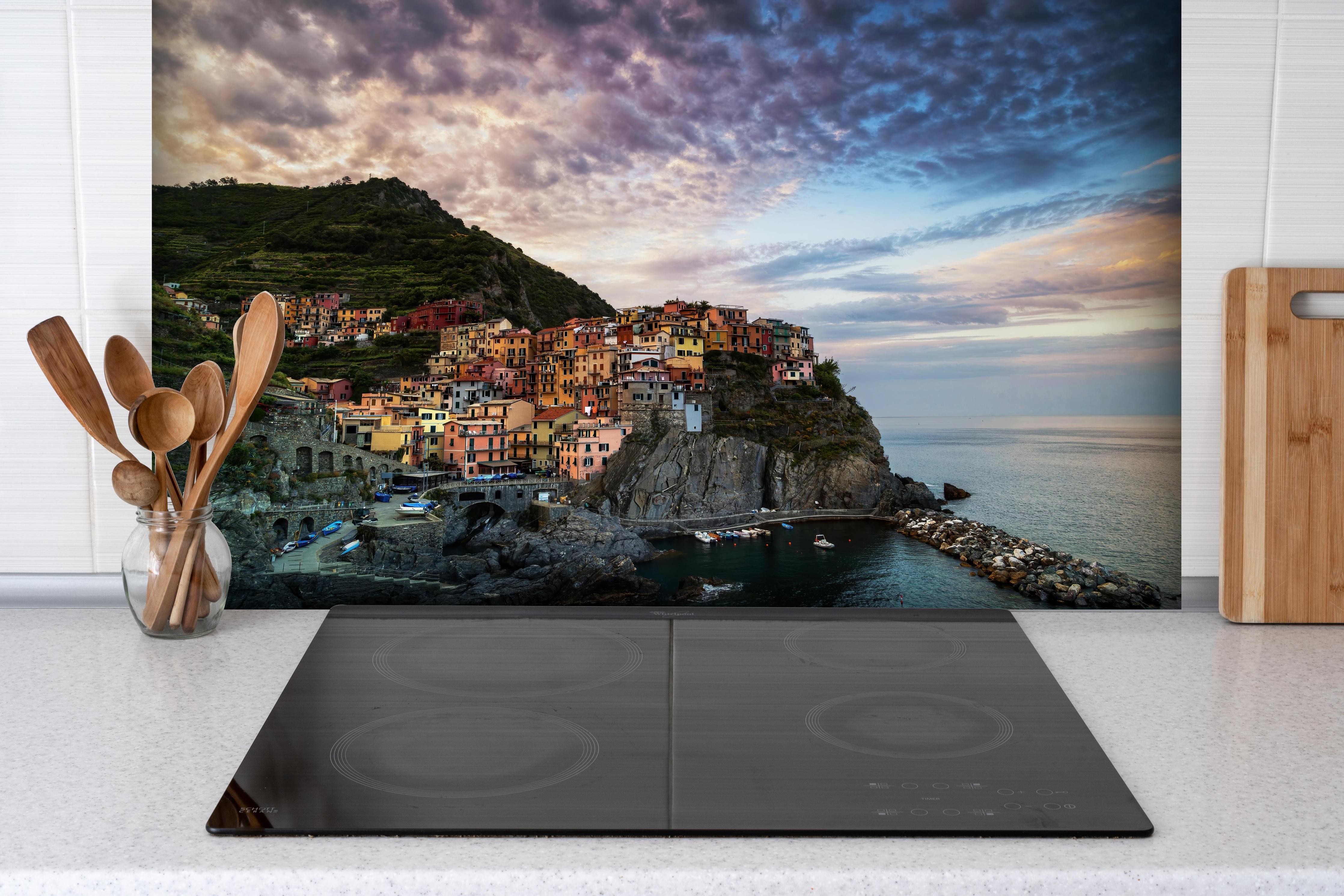 Spritzschutz - Manarola Italien Küstendämmerung hinter einem Cerankochfeld zwischen Holz-Kochutensilien
