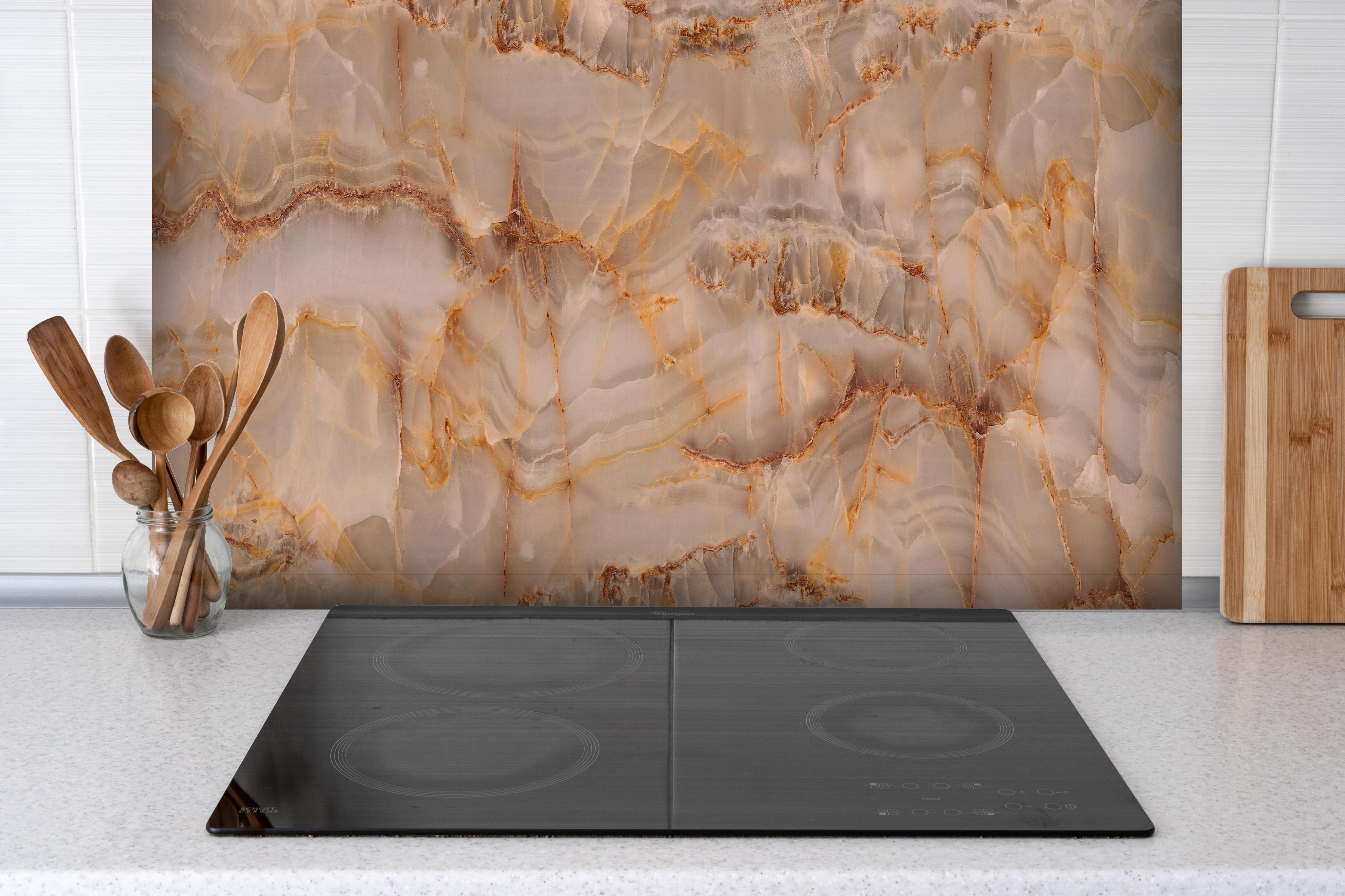 Spritzschutz - Marmor Onyx Struktur hinter einem Cerankochfeld zwischen Holz-Kochutensilien
