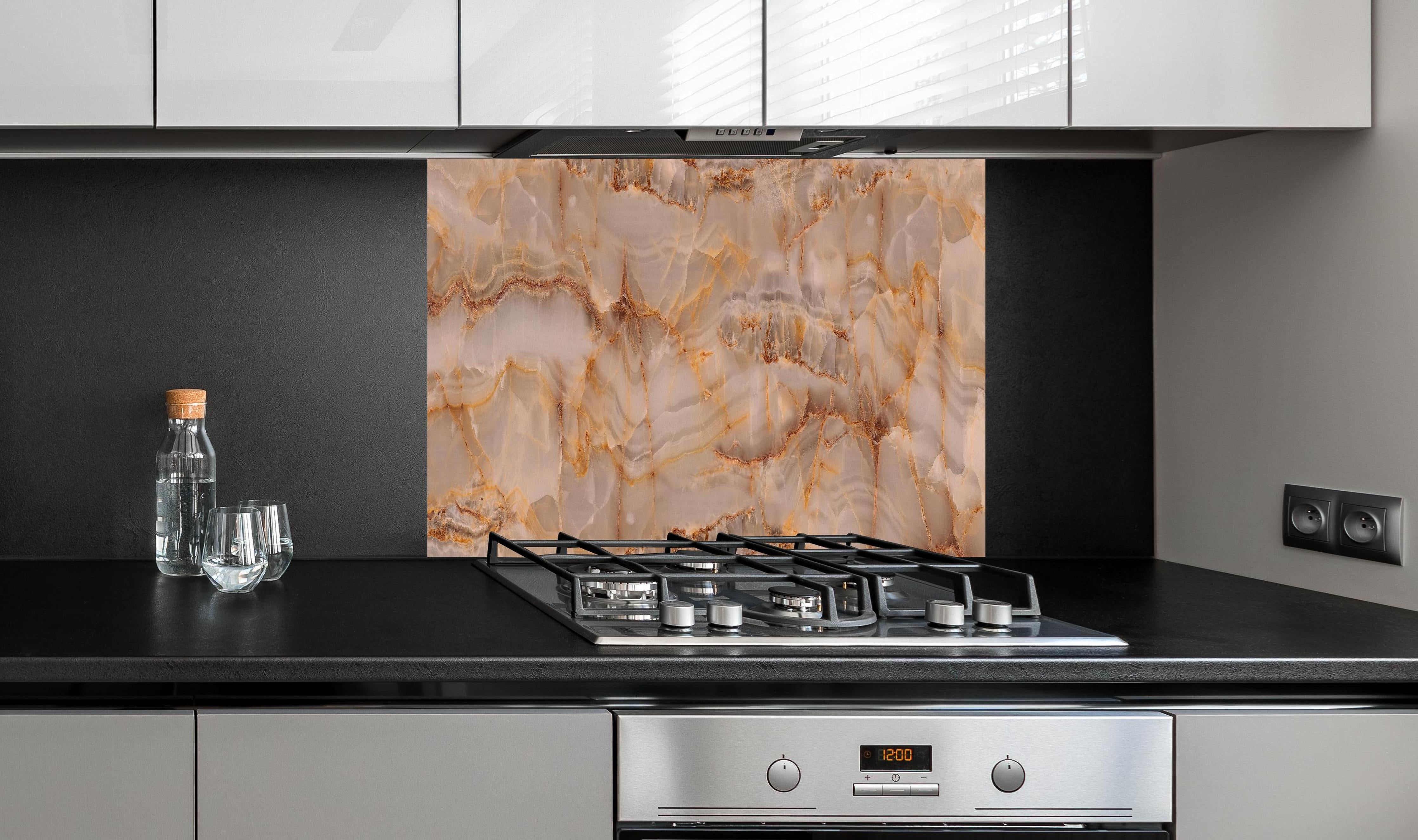 Spritzschutz - Marmor Onyx Struktur hinter einem Cerankochfeld zwischen Holz-Kochutensilien
