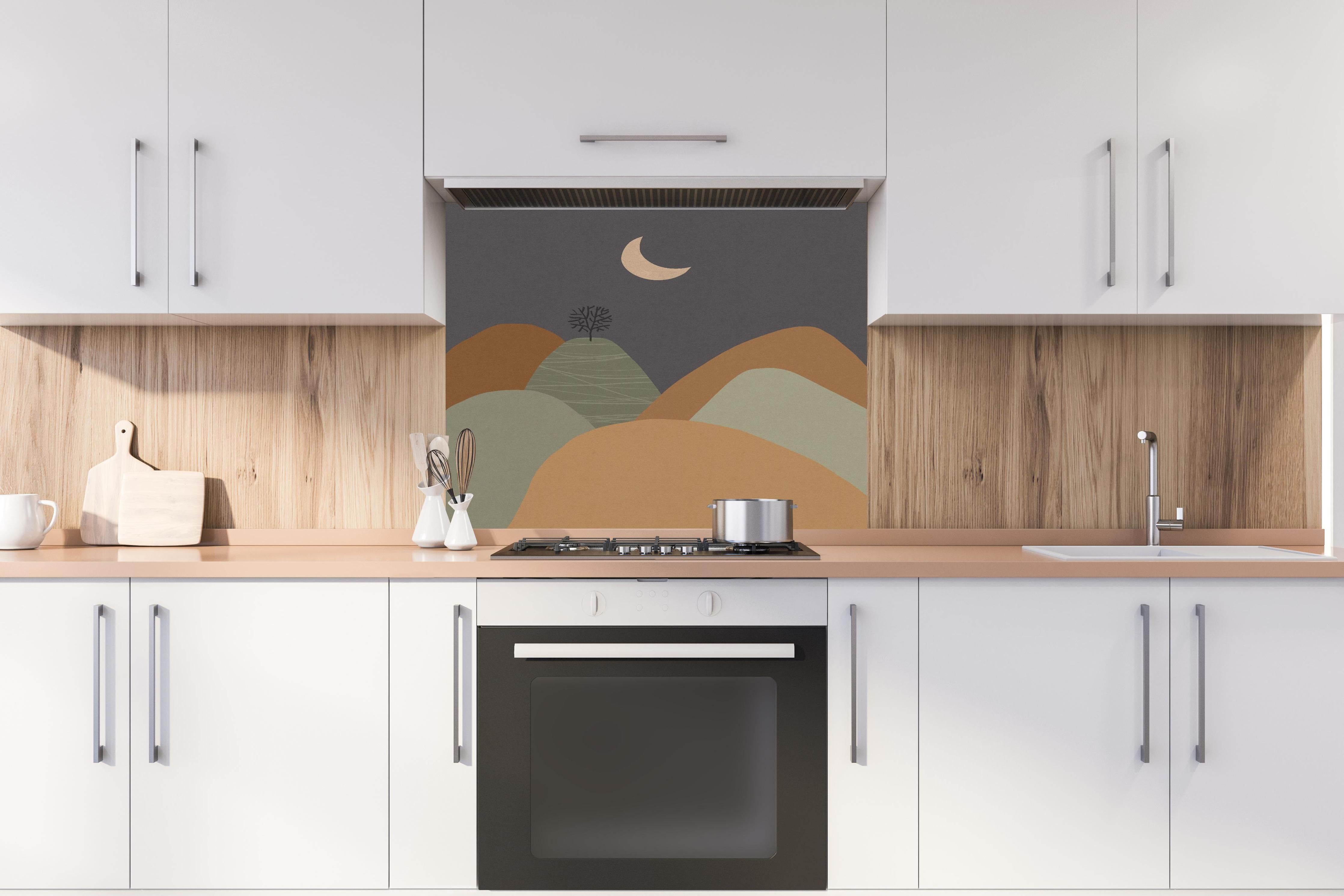 Spritzschutz - Minimalistische Baum und Berge Nacht Szene hinter einem Cerankochfeld zwischen Holz-Kochutensilien
