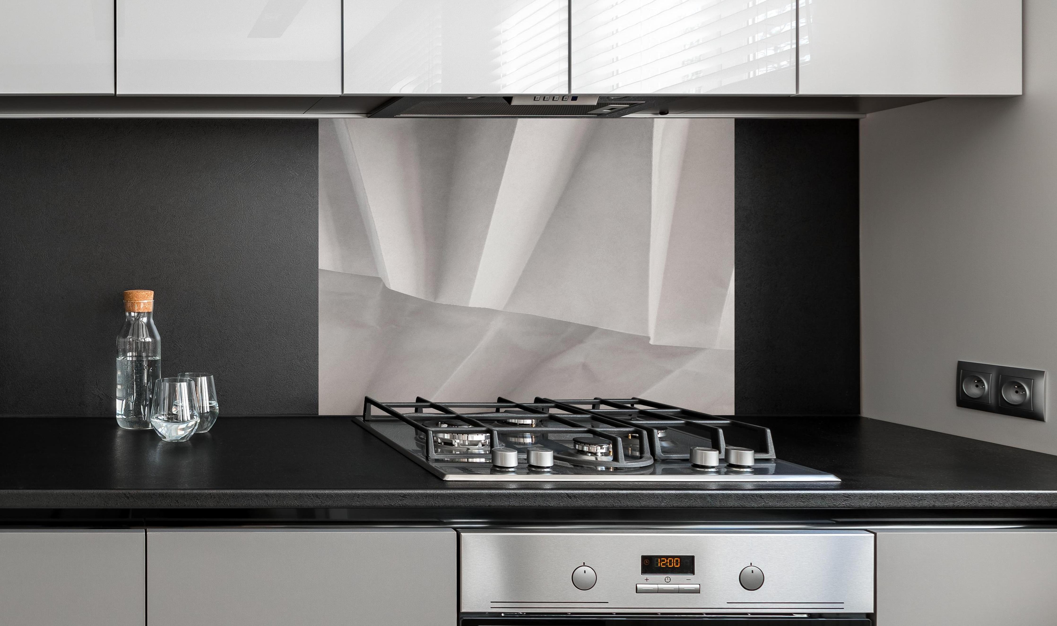 Spritzschutz - Minimalistische weiß-graue Papier Textur hinter einem Cerankochfeld zwischen Holz-Kochutensilien
