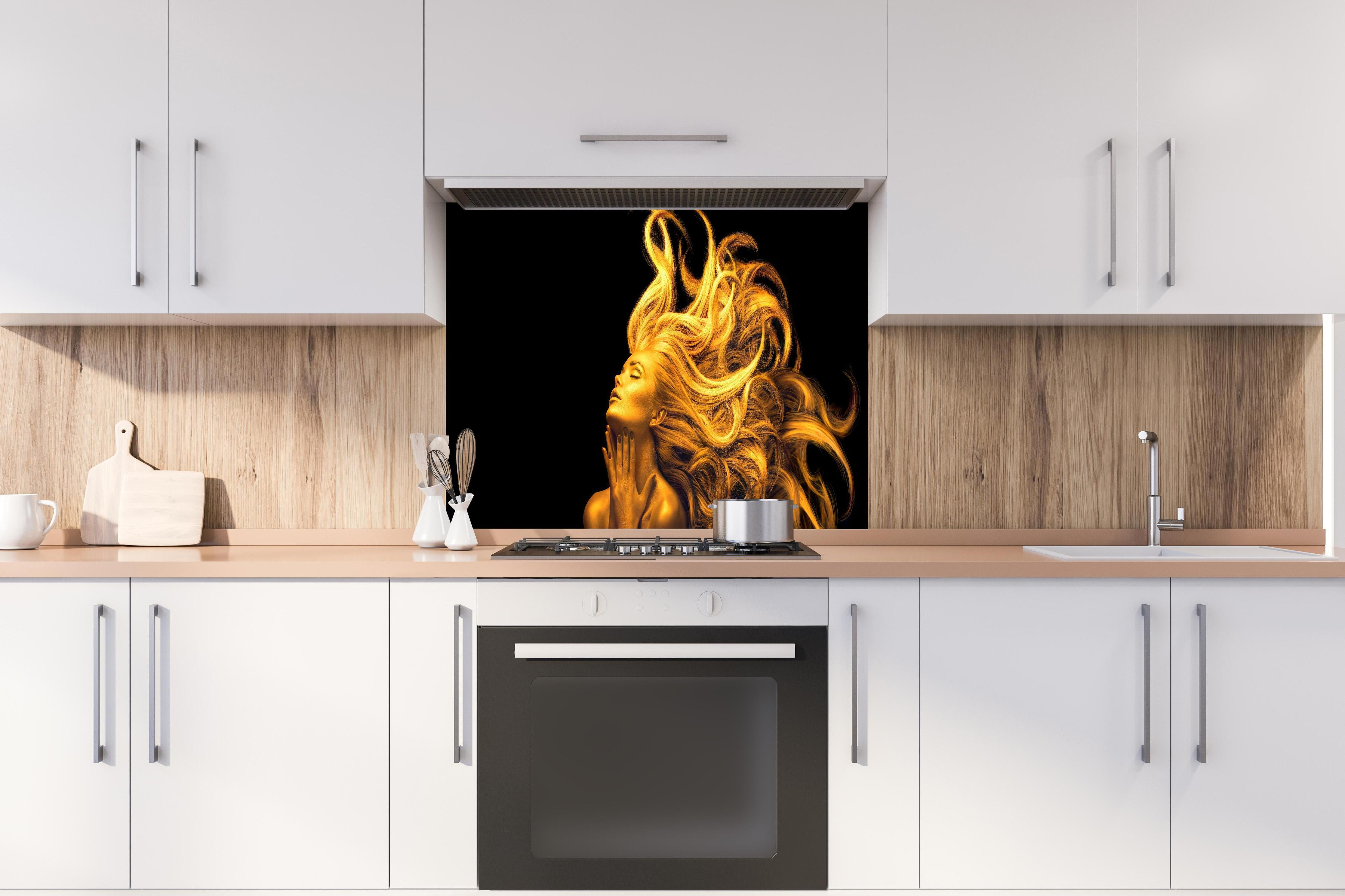 Spritzschutz - Moderne Darstellung einer vergoldeten Frau hinter einem Cerankochfeld zwischen Holz-Kochutensilien
