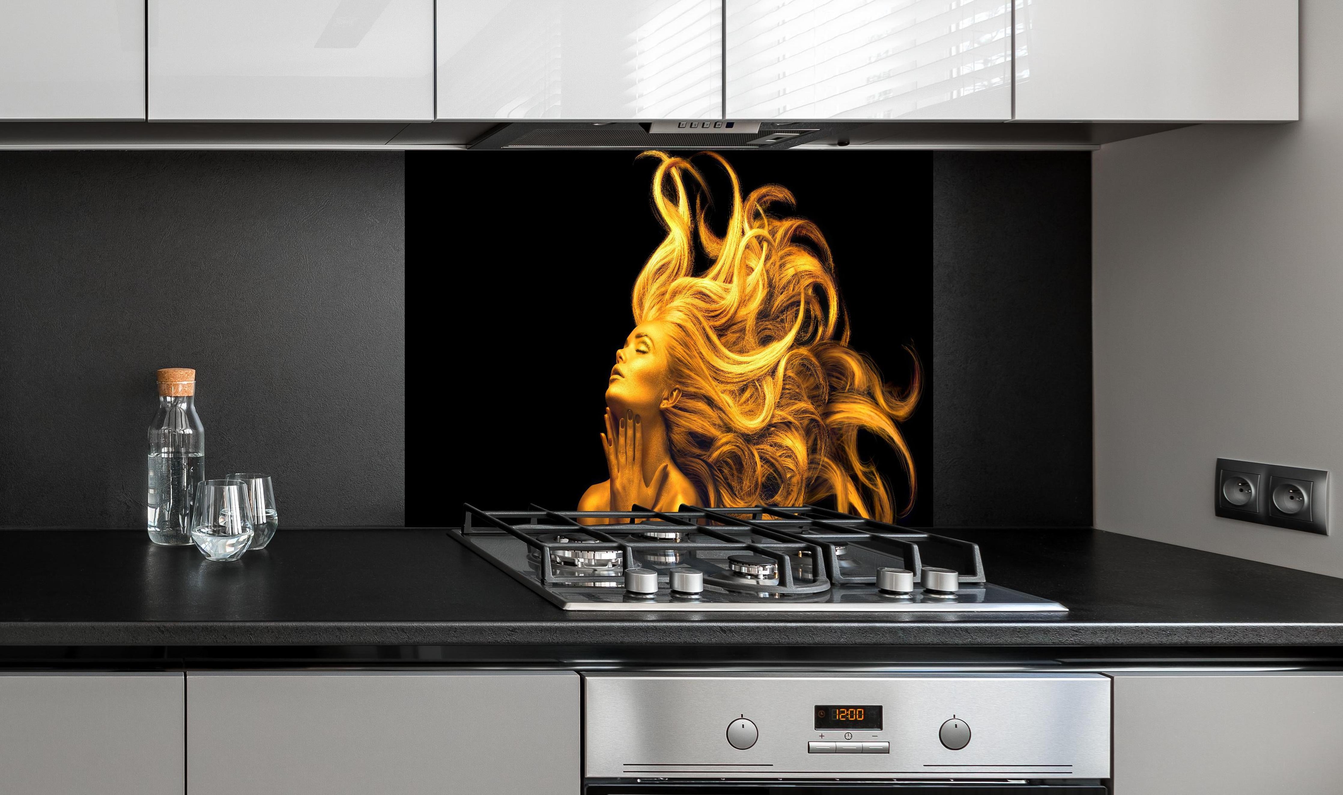 Spritzschutz - Moderne Darstellung einer vergoldeten Frau hinter einem Cerankochfeld zwischen Holz-Kochutensilien
