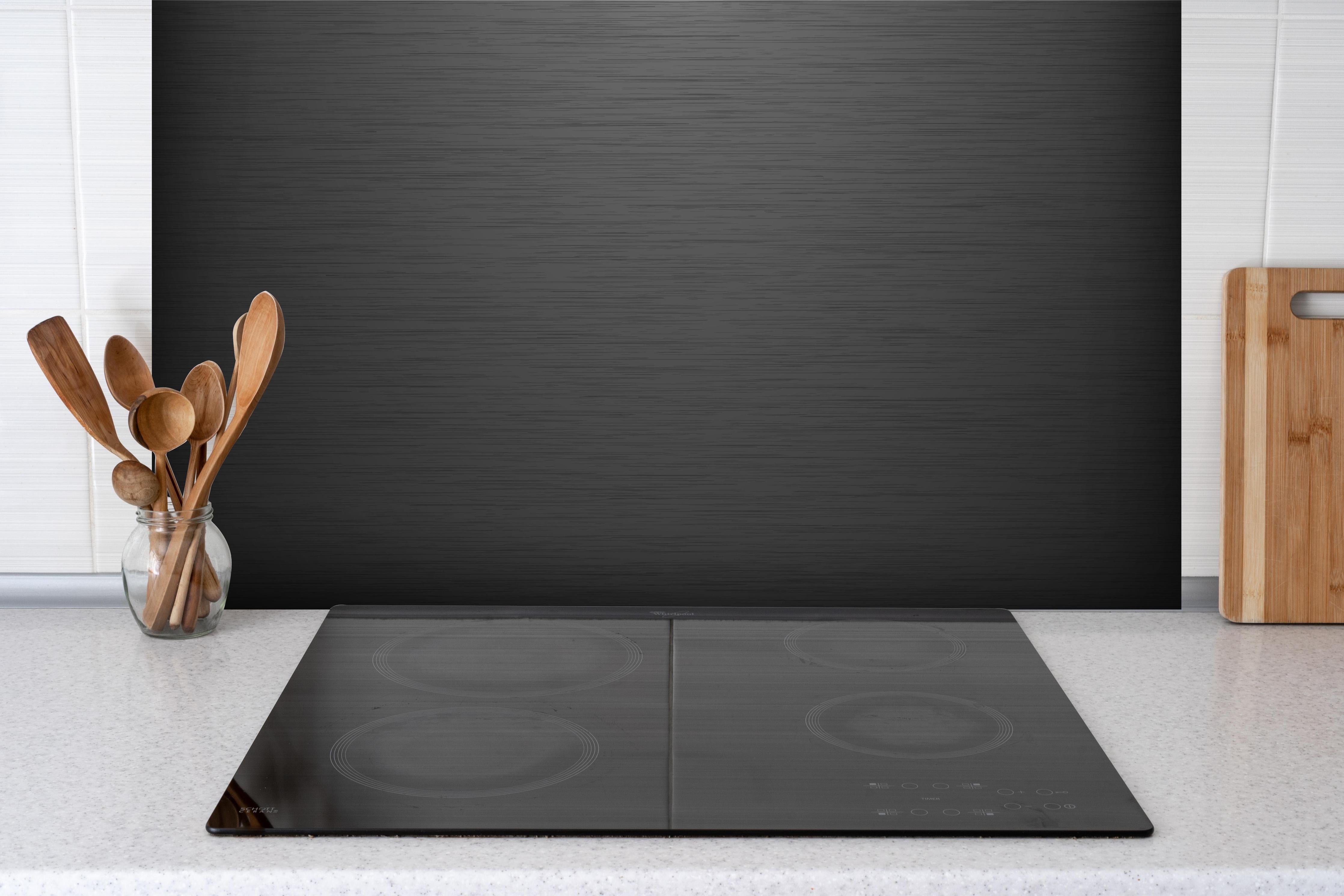 Spritzschutz - Moderne Dunkelgraue Strukturoberfläche hinter einem Cerankochfeld zwischen Holz-Kochutensilien
