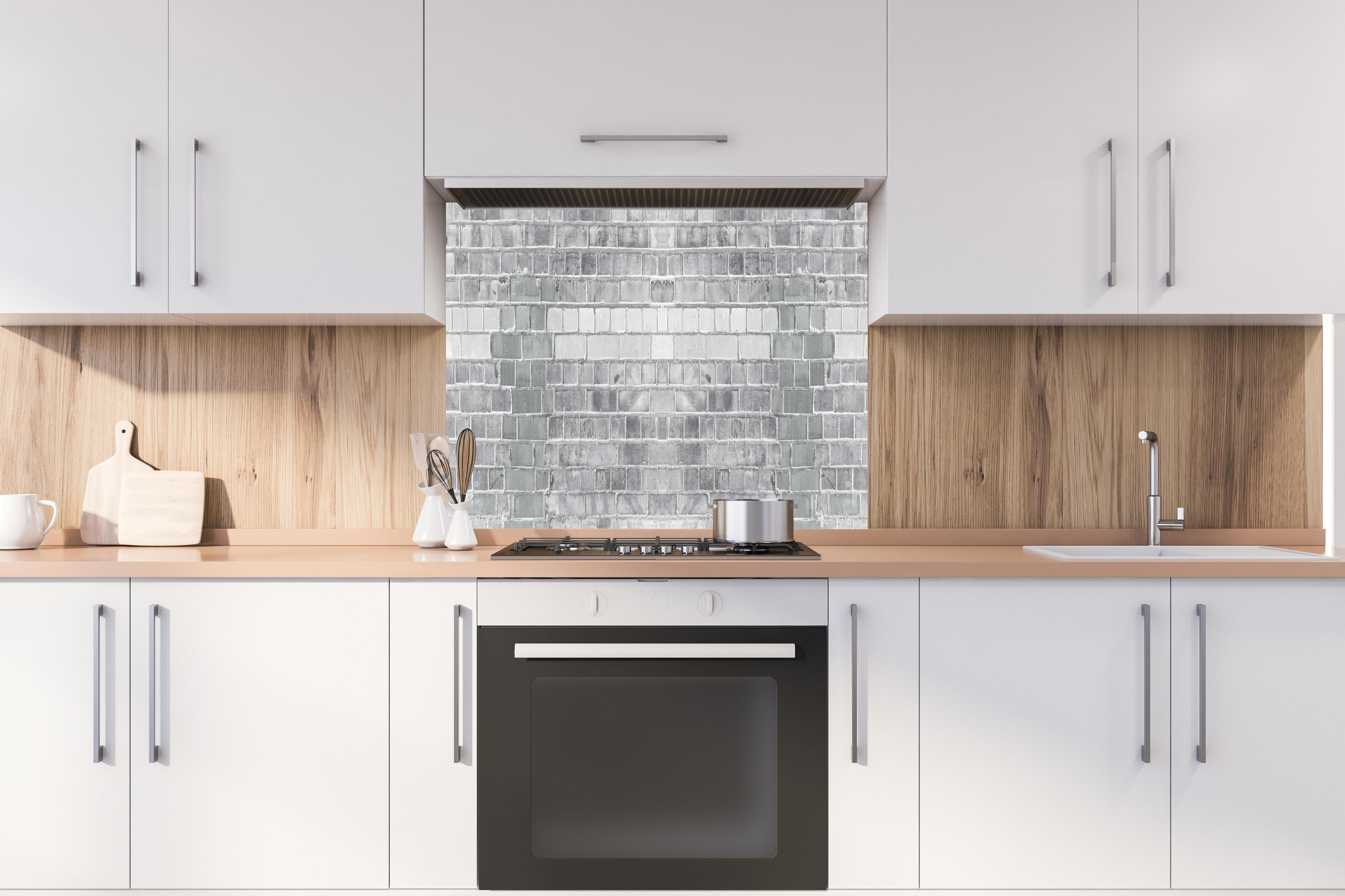 Spritzschutz - Moderne weiße Backsteinwand mit Grautönen hinter einem Cerankochfeld zwischen Holz-Kochutensilien
