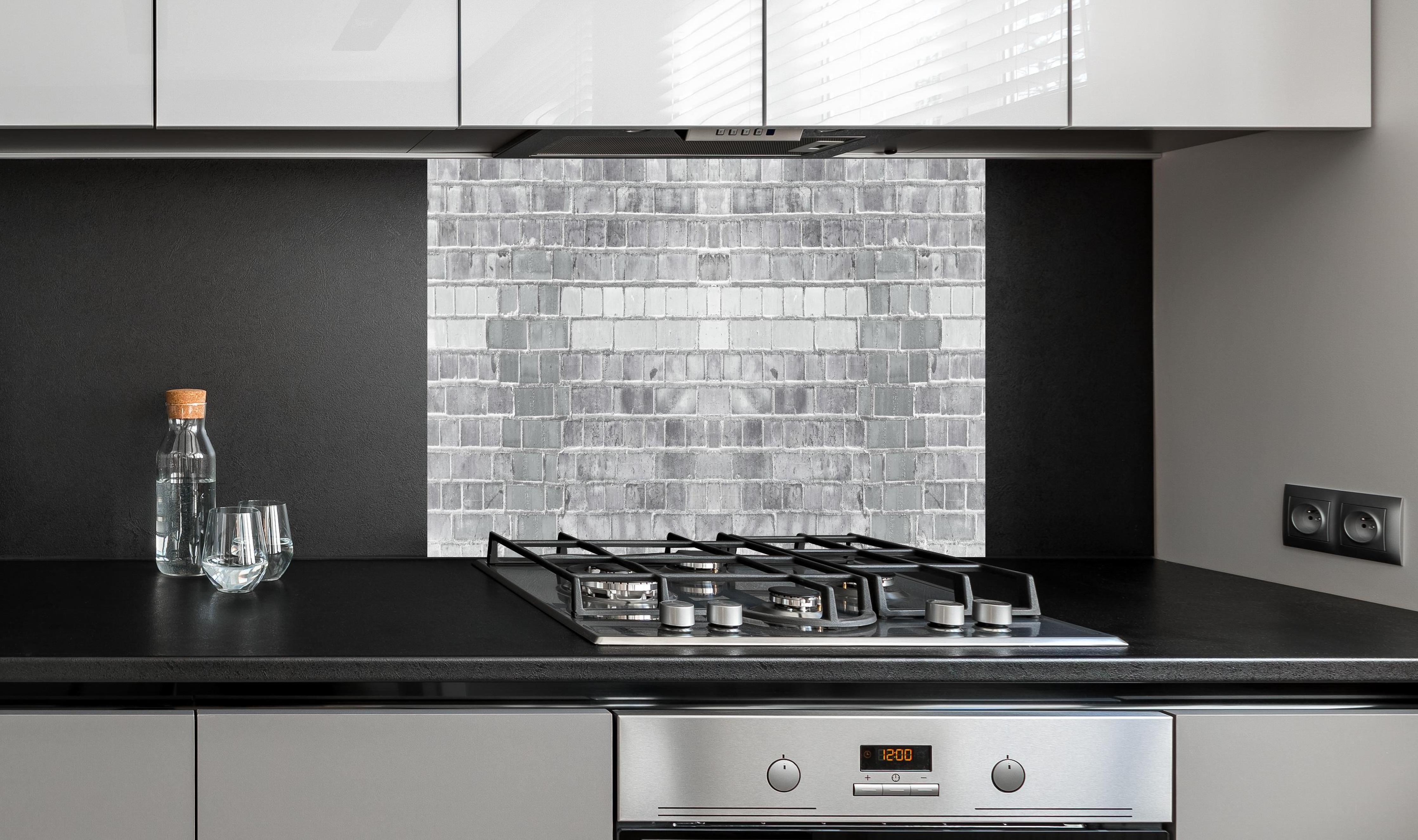 Spritzschutz - Moderne weiße Backsteinwand mit Grautönen hinter einem Cerankochfeld zwischen Holz-Kochutensilien
