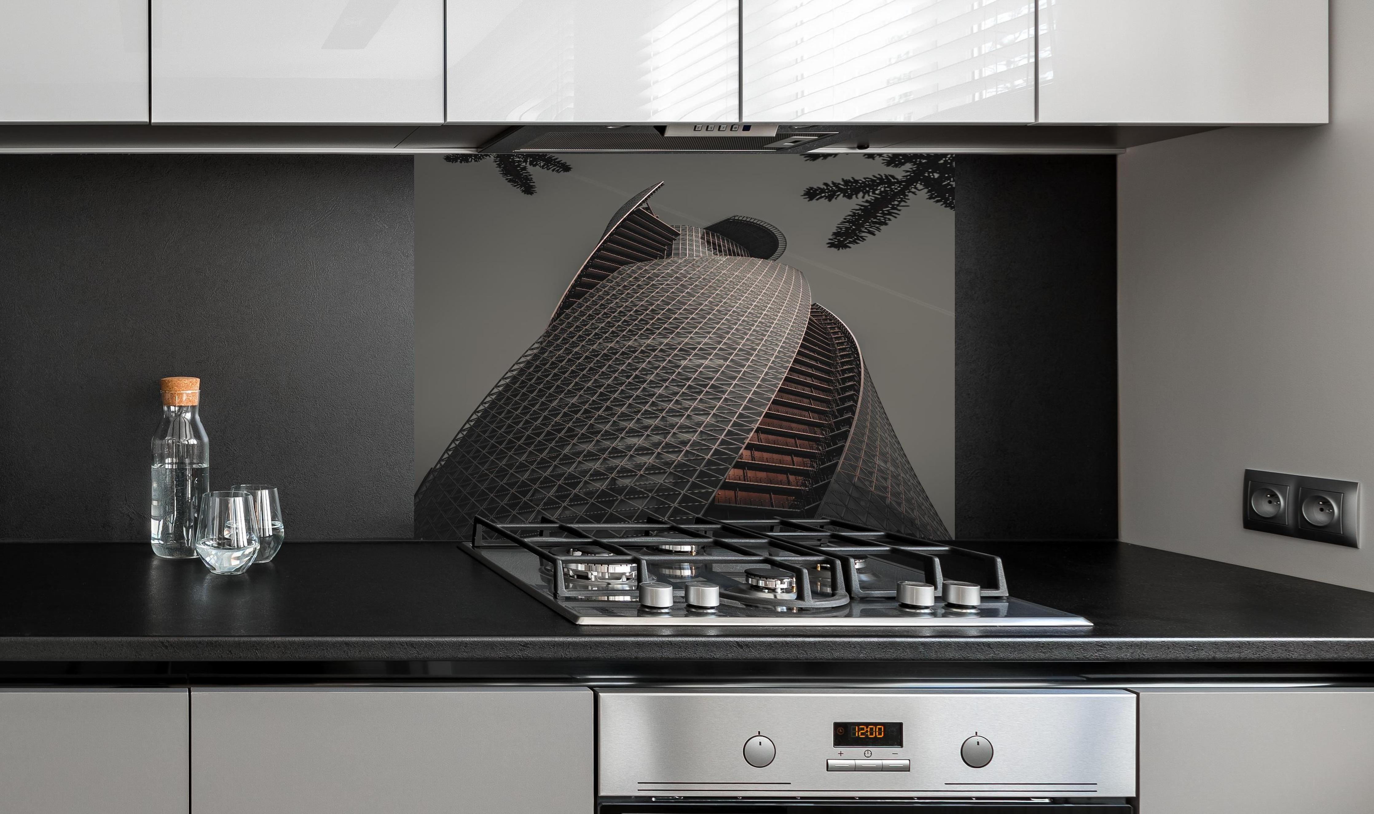 Spritzschutz - Modernes Spiral-Gebäude in Grautönen hinter einem Cerankochfeld zwischen Holz-Kochutensilien
