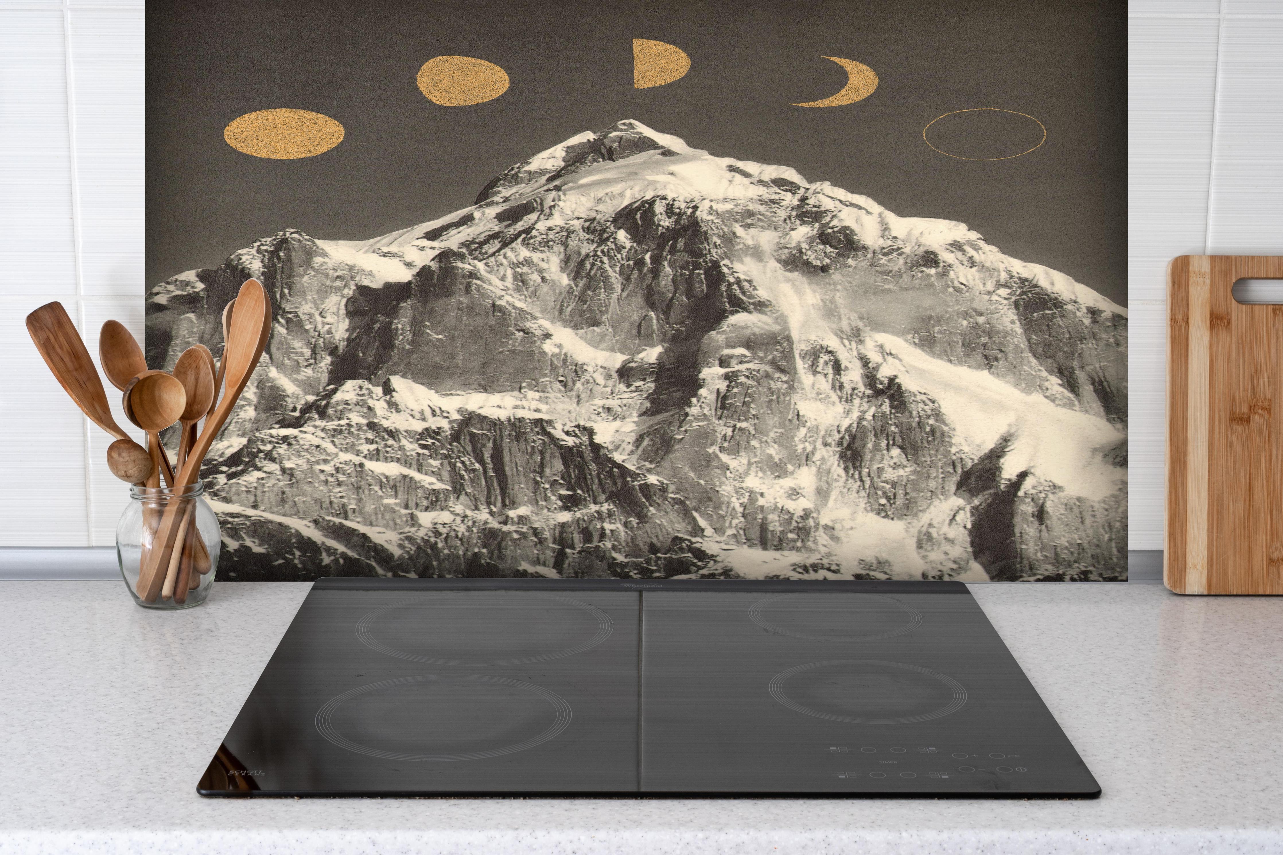 Spritzschutz - Monochrome Mondphasen über schneebedecktem Berg hinter einem Cerankochfeld zwischen Holz-Kochutensilien
