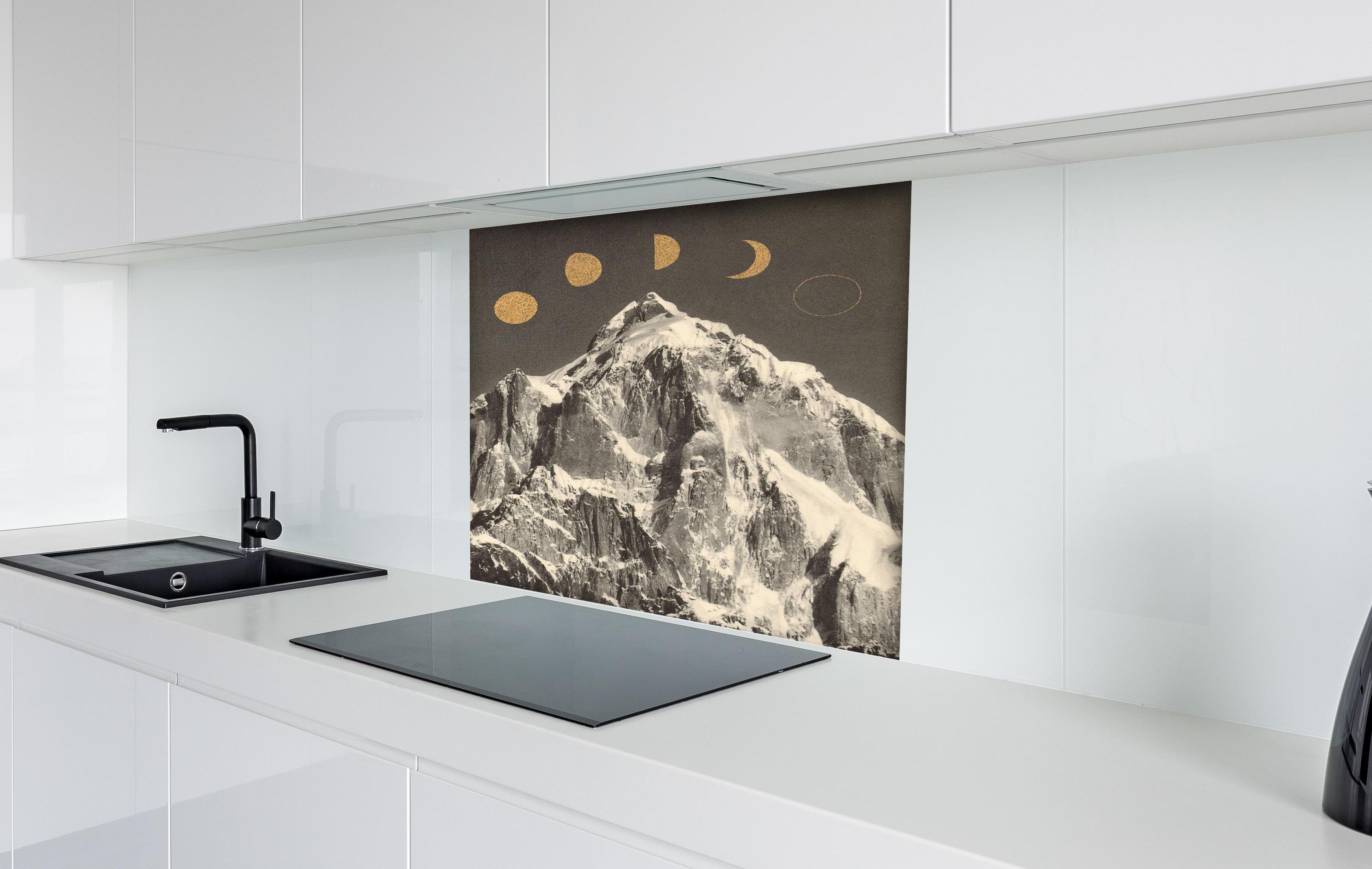 Spritzschutz - Monochrome Mondphasen über schneebedecktem Berg hinter einem Cerankochfeld zwischen Holz-Kochutensilien
