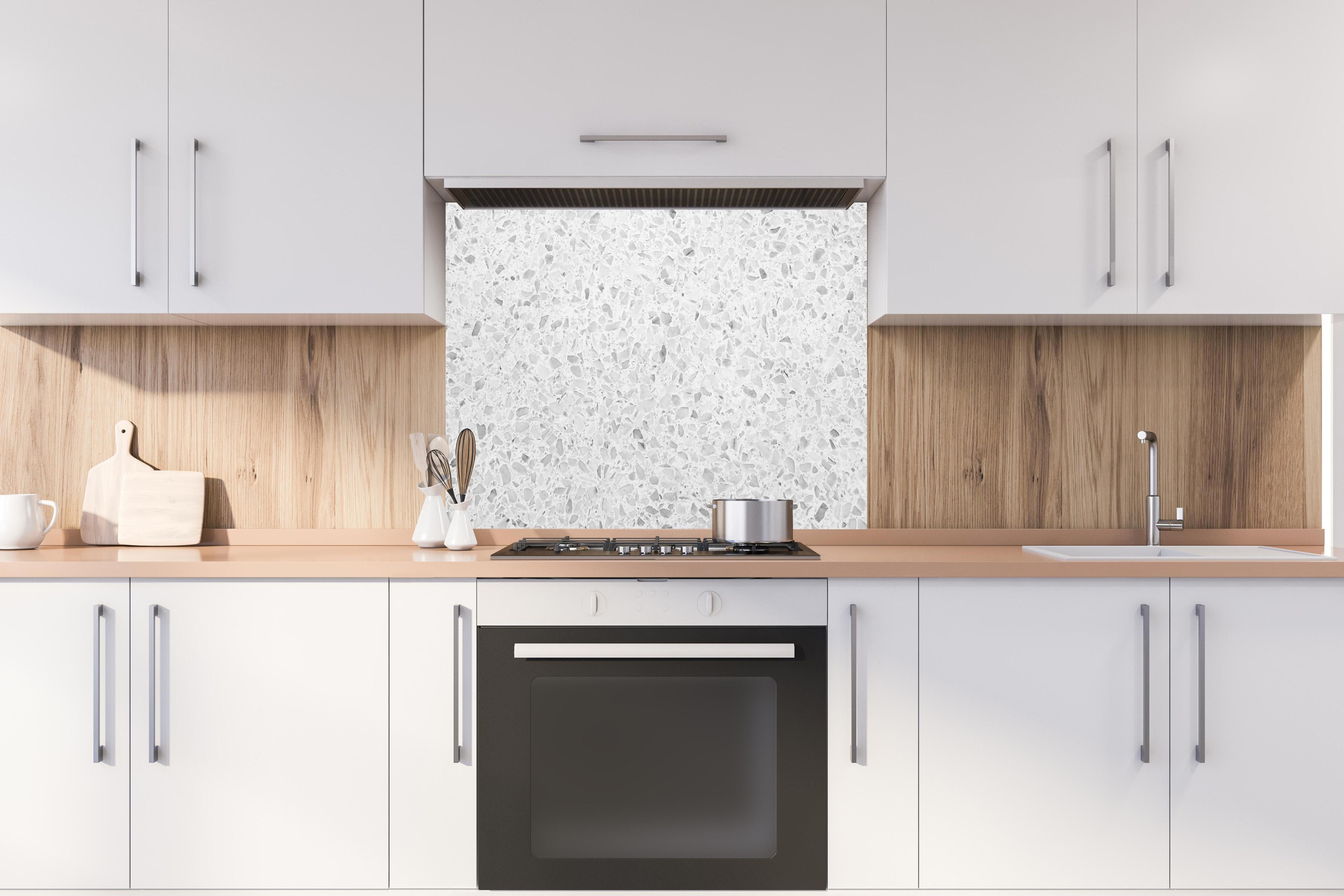 Spritzschutz - Monochrome Weiβ-Graue Terrazzo-Textur hinter einem Cerankochfeld zwischen Holz-Kochutensilien
