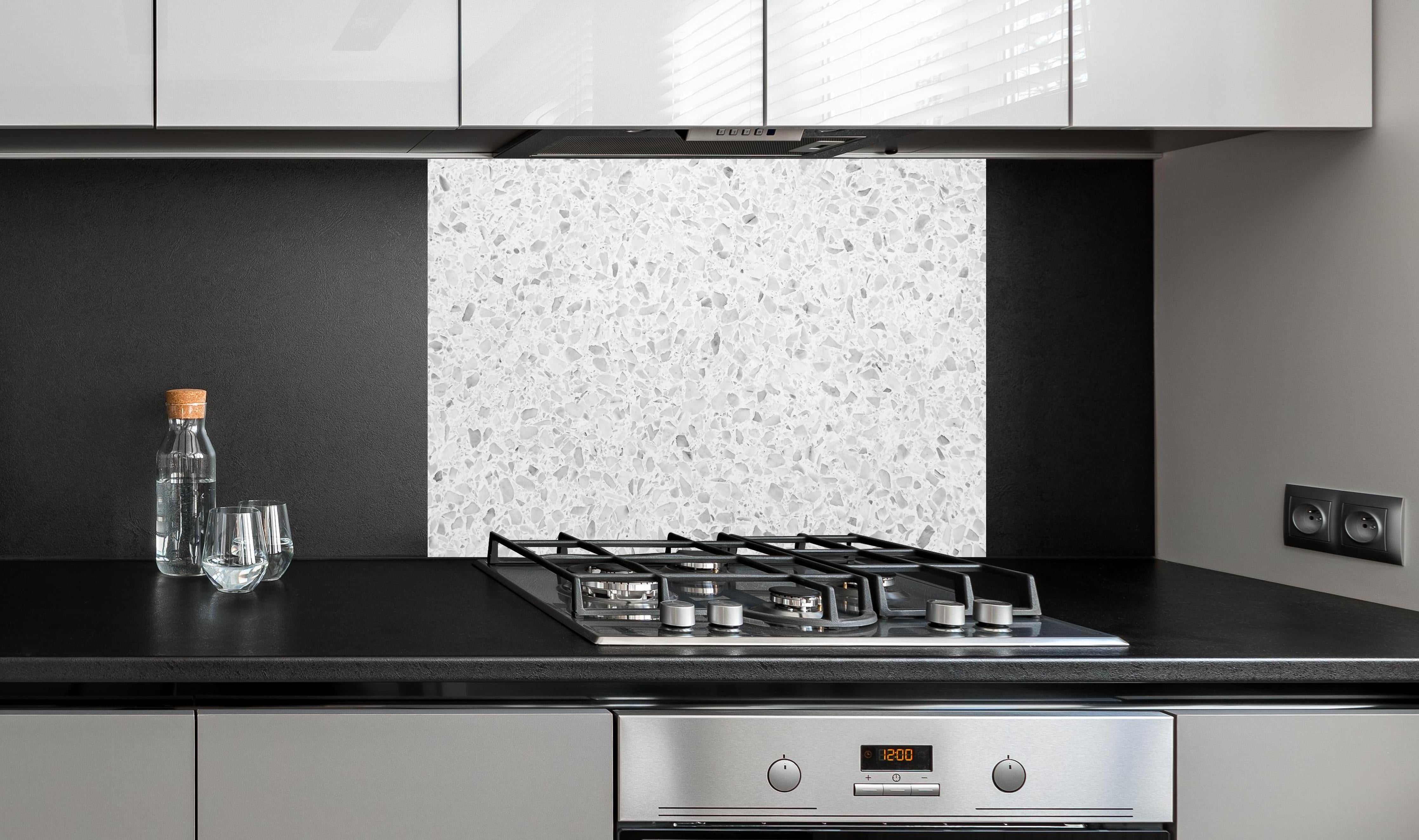 Spritzschutz - Monochrome Weiβ-Graue Terrazzo-Textur hinter einem Cerankochfeld zwischen Holz-Kochutensilien
