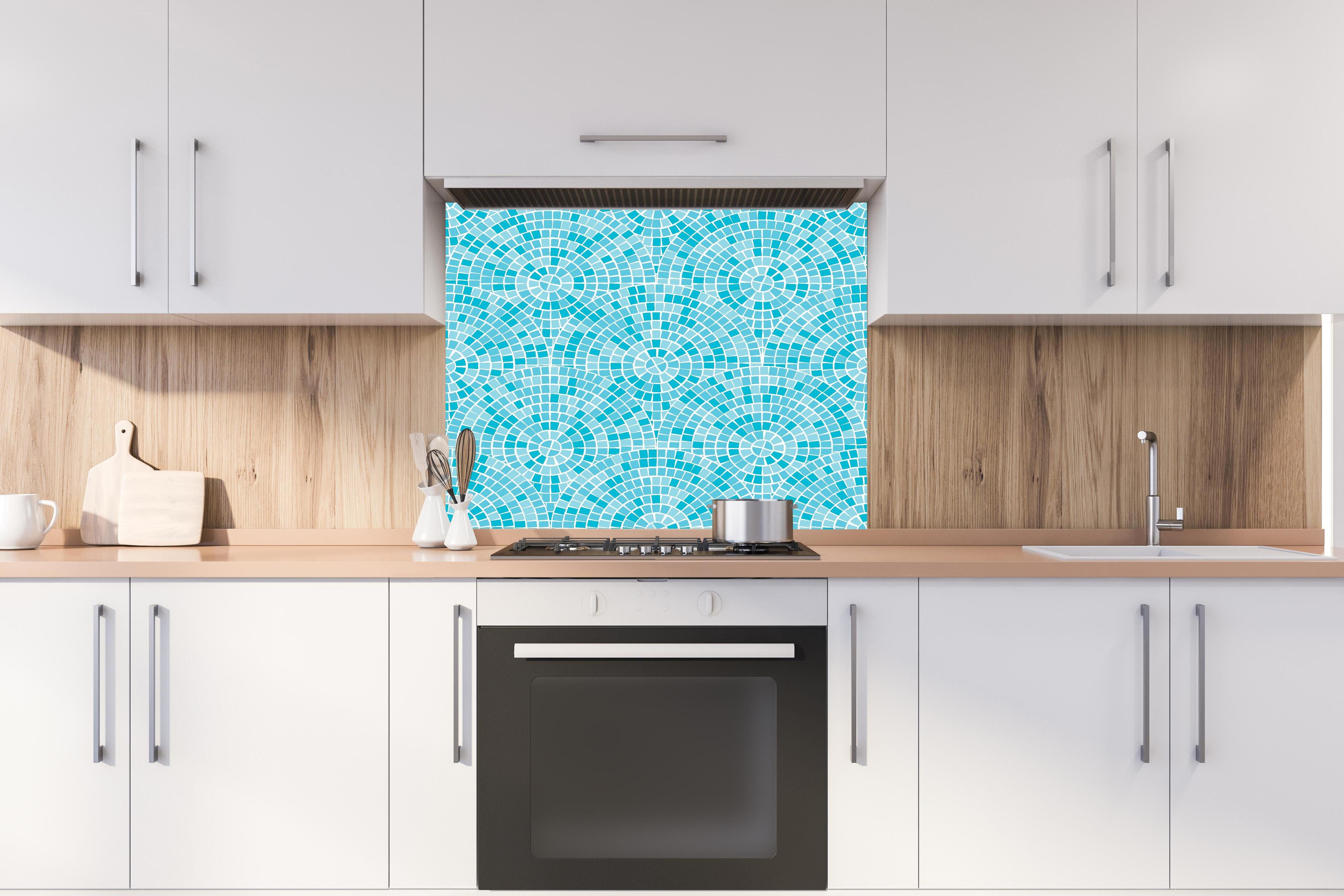 Spritzschutz - Mosaik-Design in Türkisblau mit geometrischen Mustern hinter einem Cerankochfeld zwischen Holz-Kochutensilien
