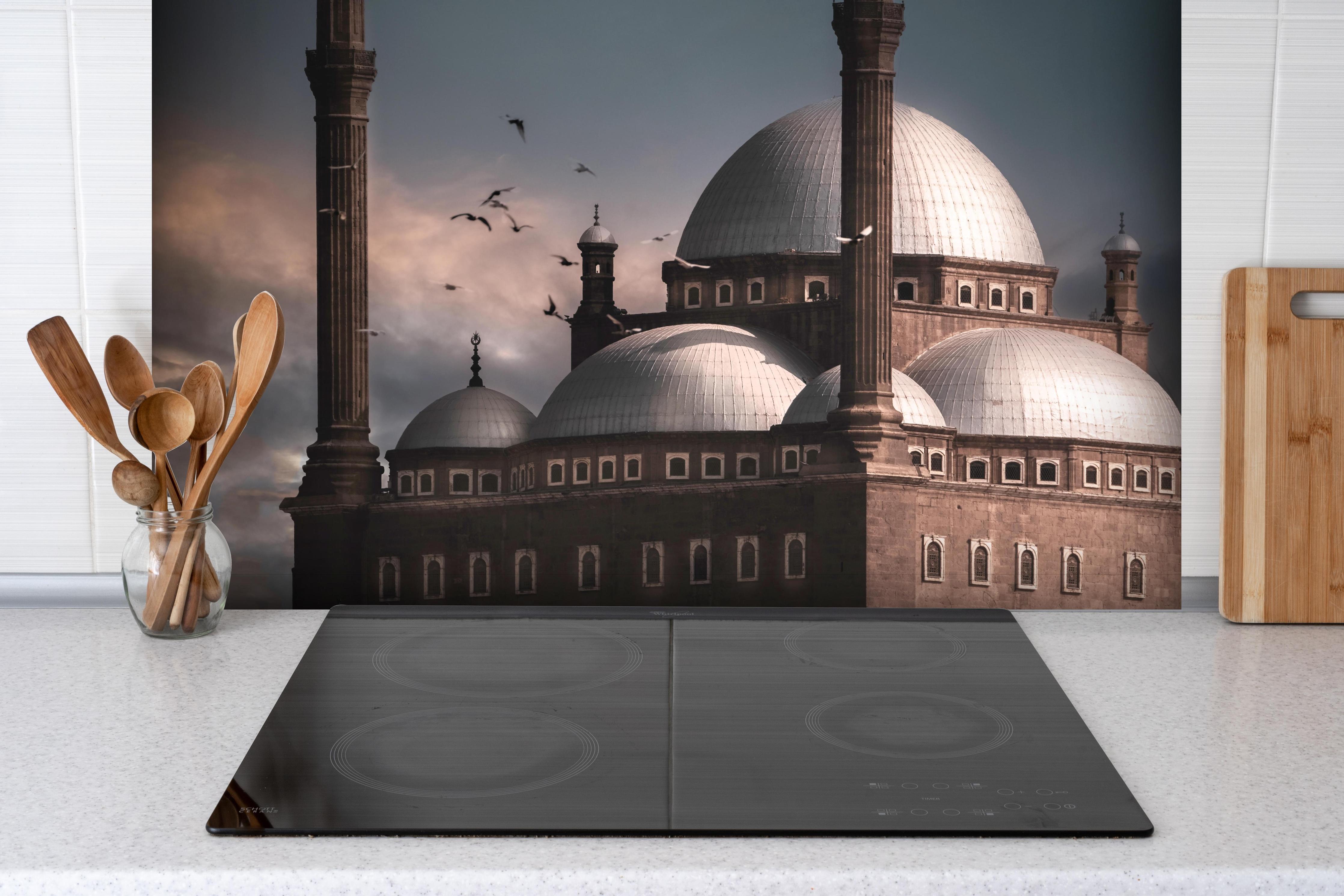 Spritzschutz - Moschee hinter einem Cerankochfeld zwischen Holz-Kochutensilien
