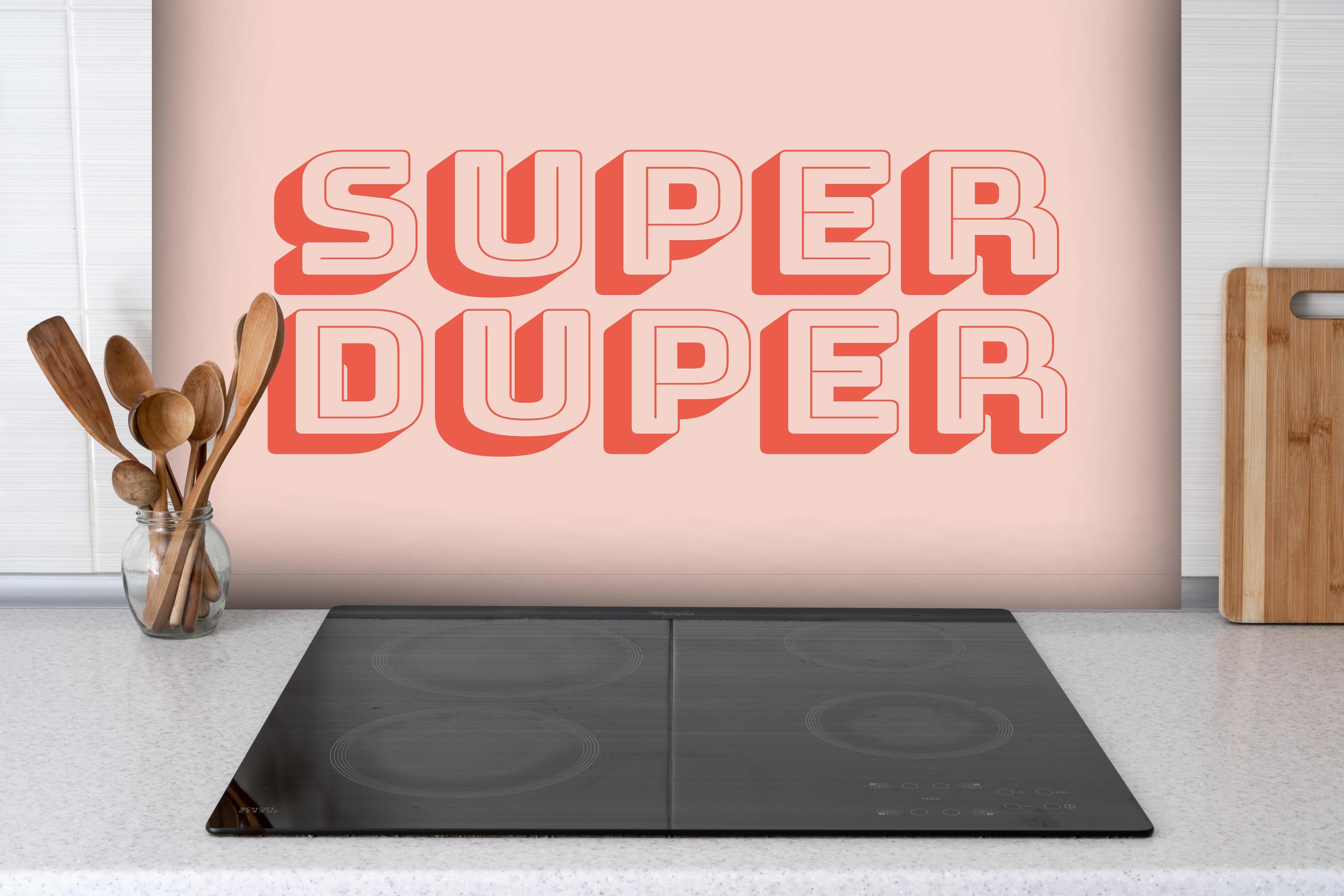 Spritzschutz - Motivationaler 'Super Duper' Schriftzug in Pink hinter einem Cerankochfeld zwischen Holz-Kochutensilien

