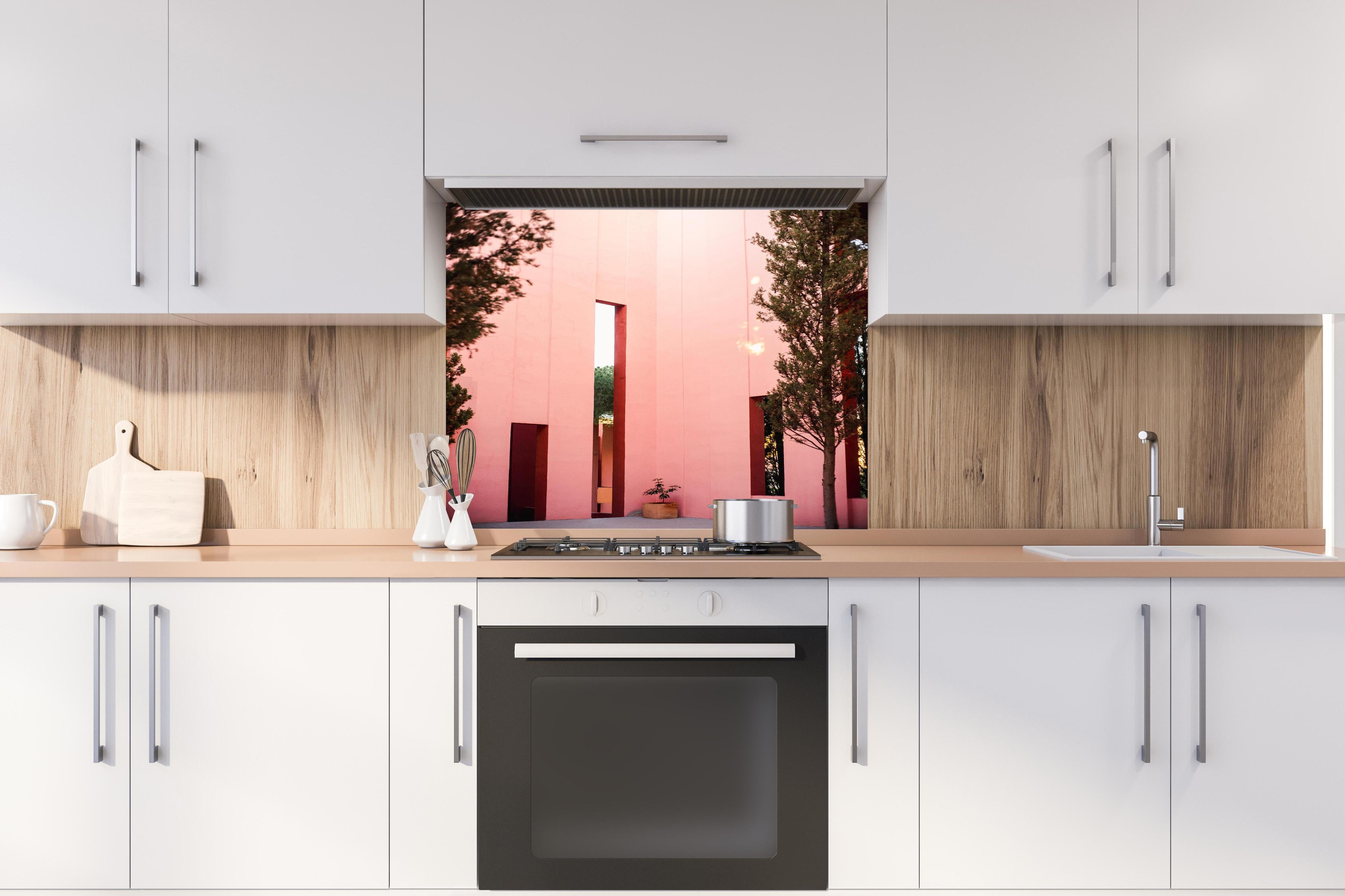 Spritzschutz - Muralla Roja Eingang in zartem Pink hinter einem Cerankochfeld zwischen Holz-Kochutensilien
